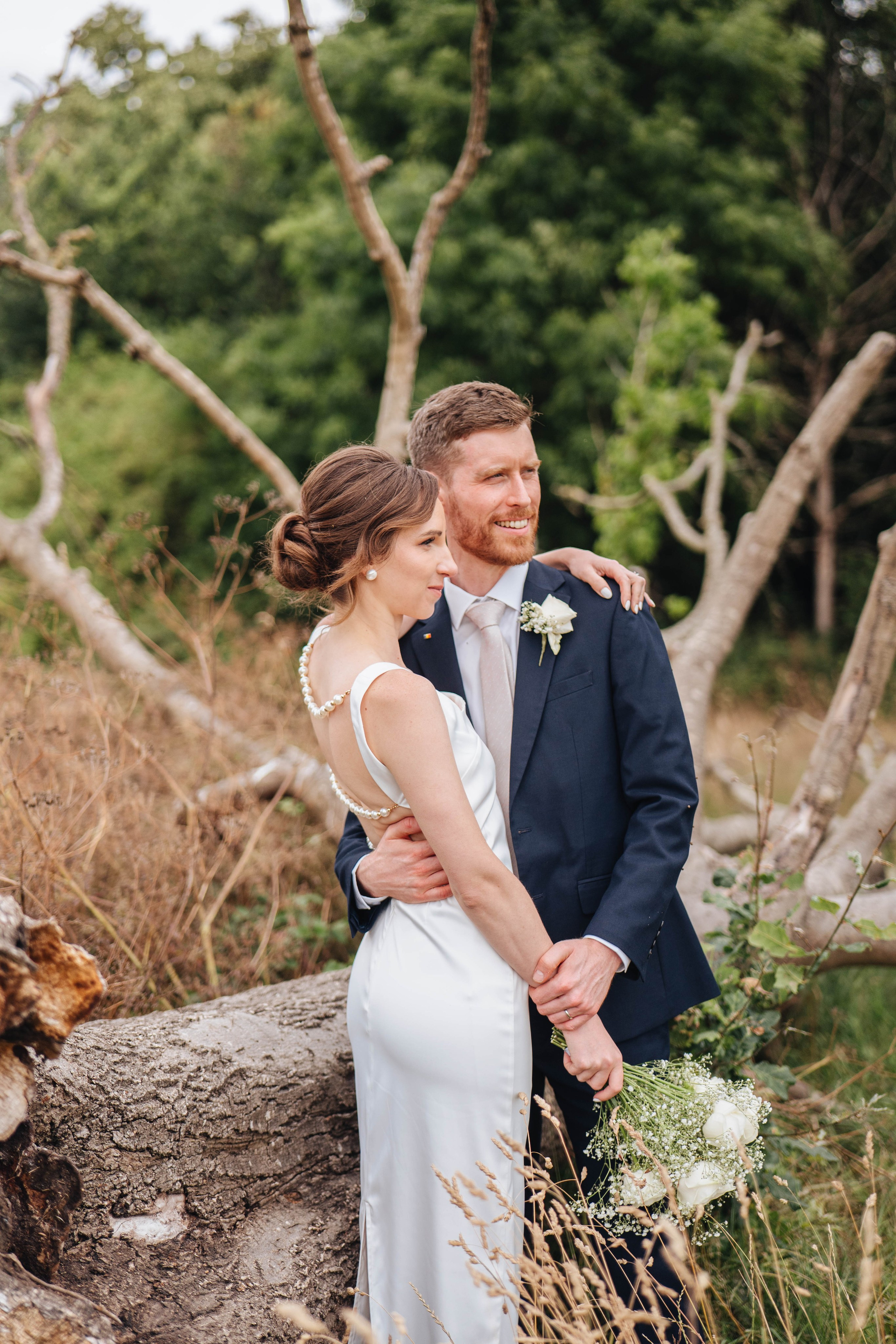 bride and groom posing near an old dead tree
