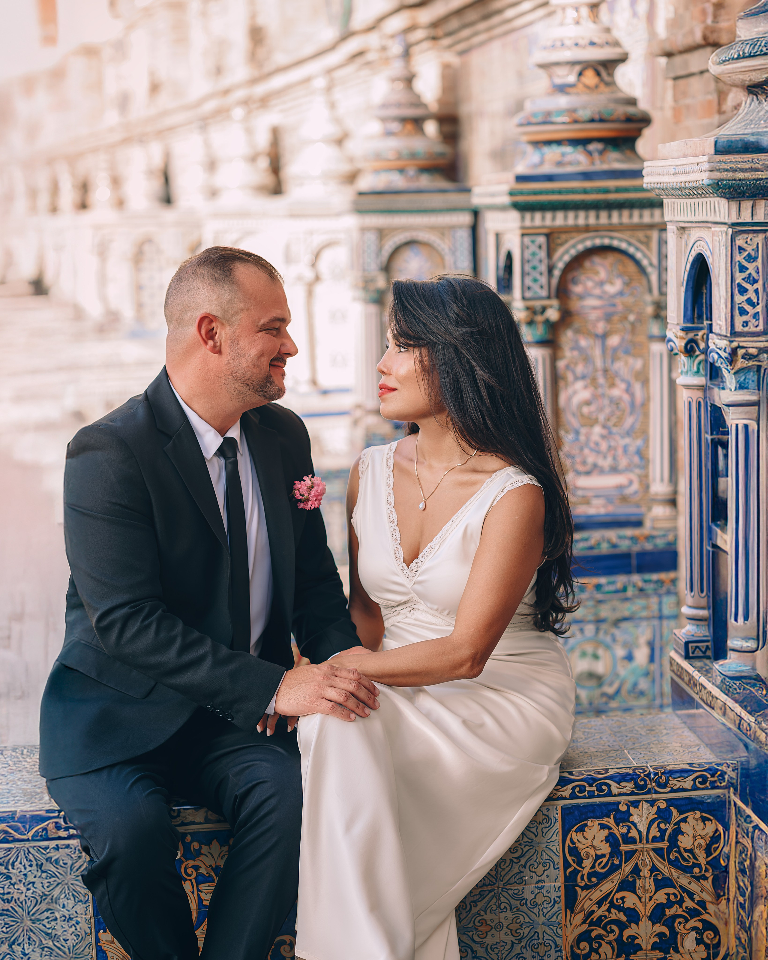 Romantic wedding portrait of a couple seated at the beautifully tiled benches of Plaza de España in Sevilla, Spain — perfect for couples seeking timeless and artistic wedding photoshoots in Seville and southern Spain.