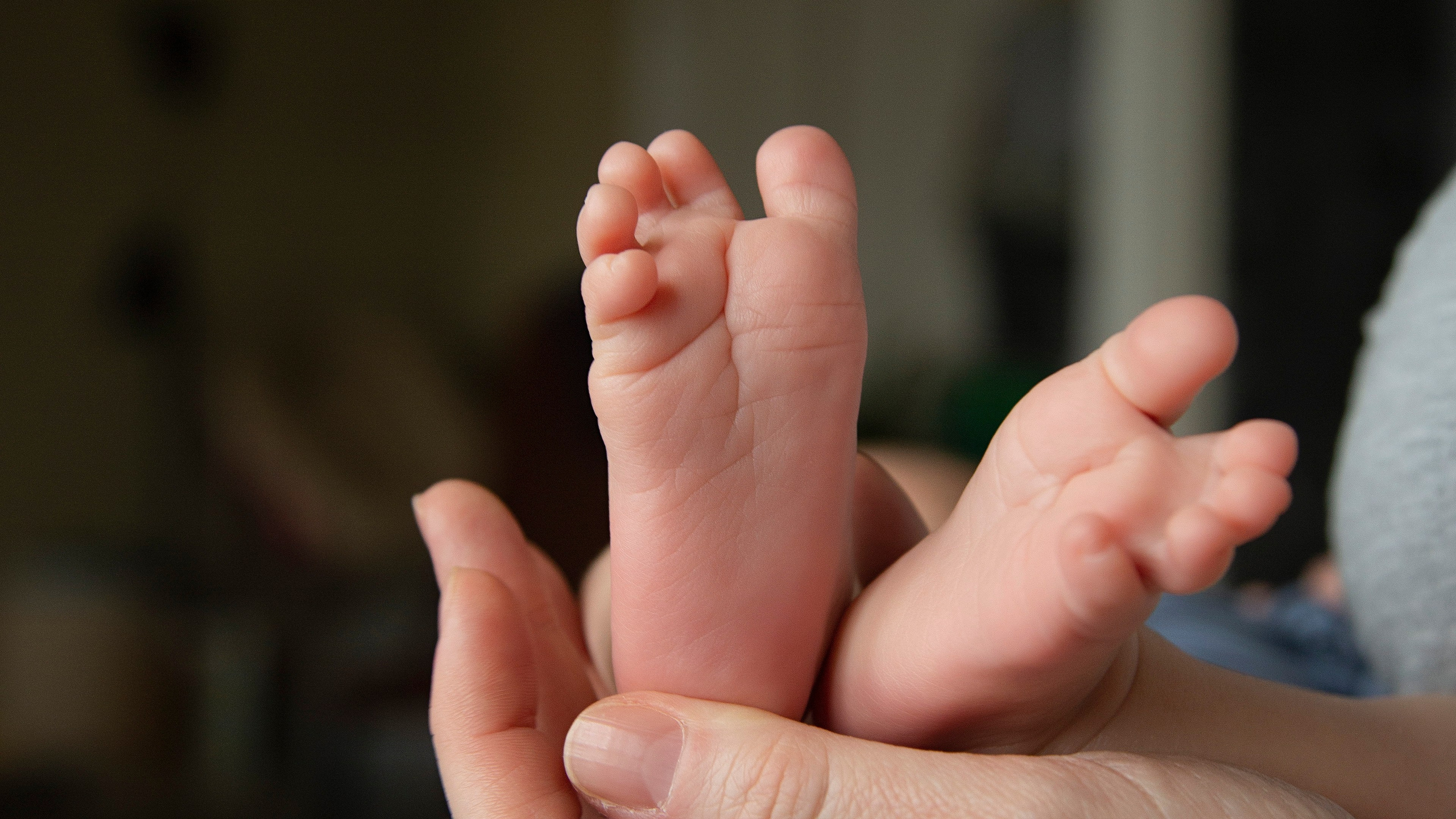 Newborn baby's feet cradled in mother's hands, symbolizing the tenderness and protection of maternal love