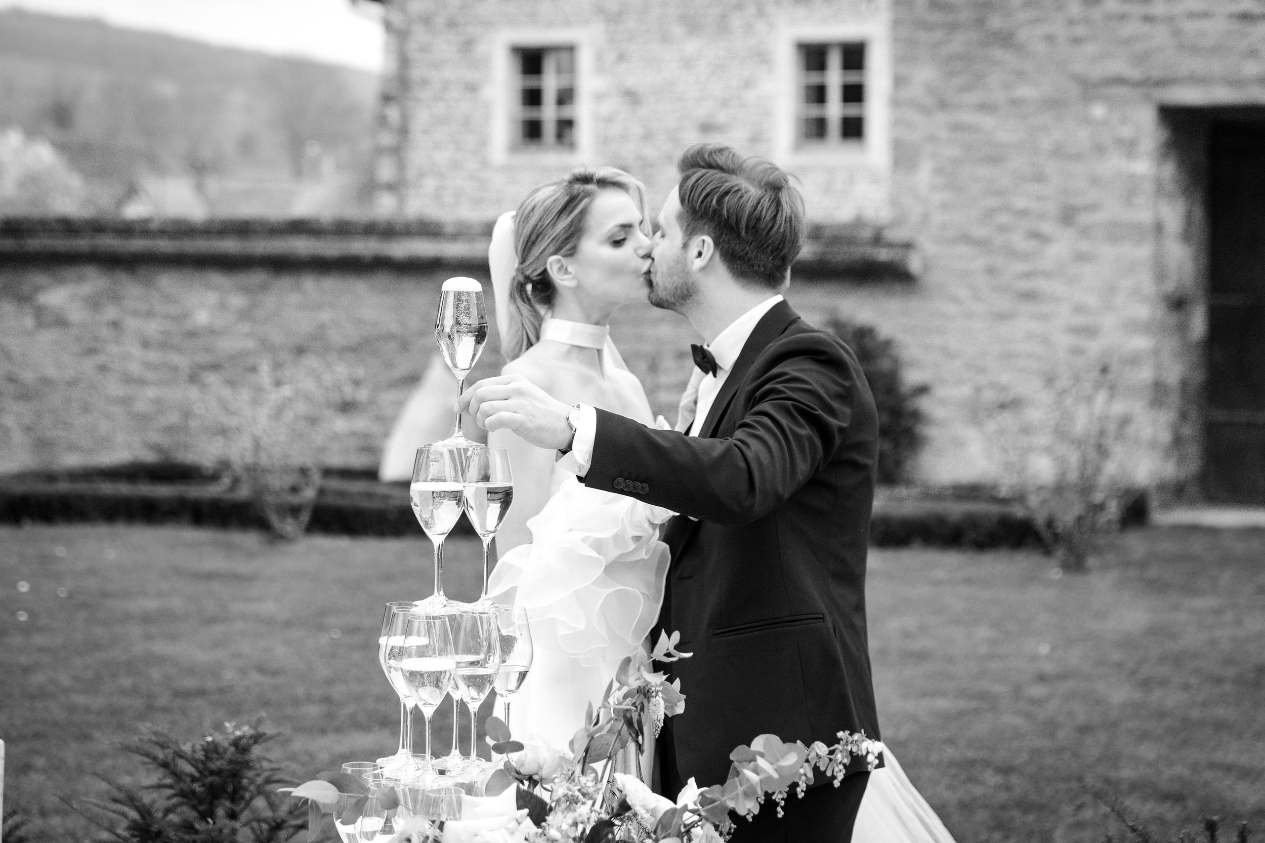 Candid moment of bride and groom kissing and drinking wine during their wedding ceremony in France. 