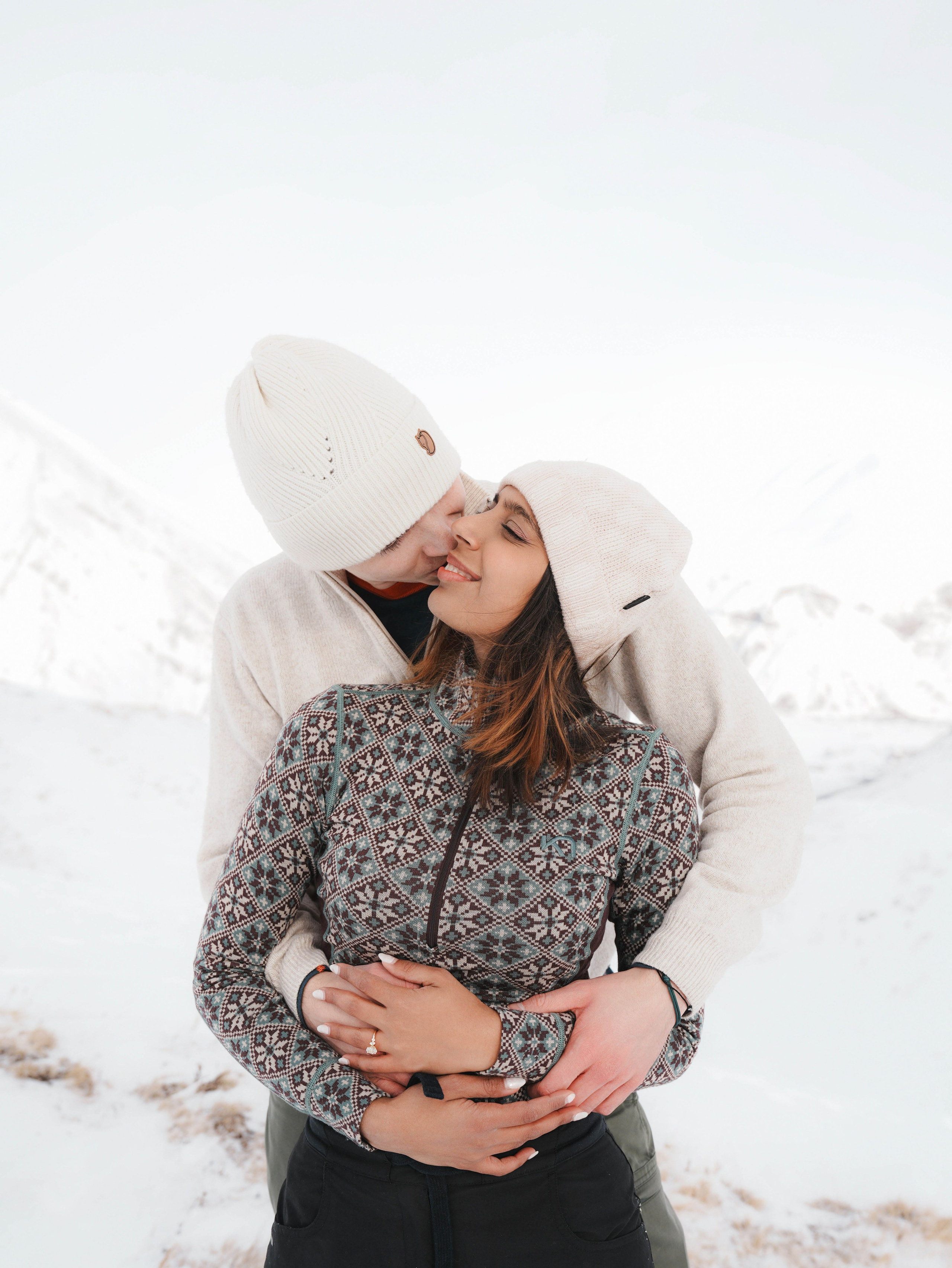 Couple hugging in snow after proposal in mountains
