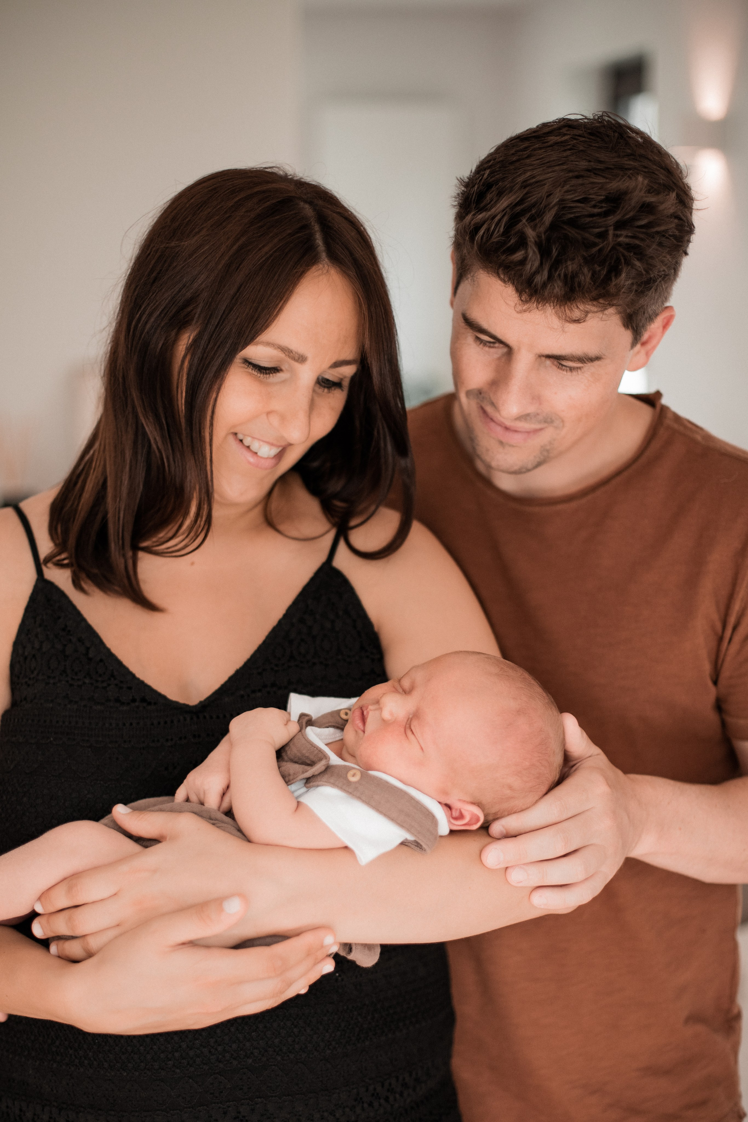 Auf dem Familienporträt schauen Mutter und Vater liebevoll auf ihren kleinen Sohn.