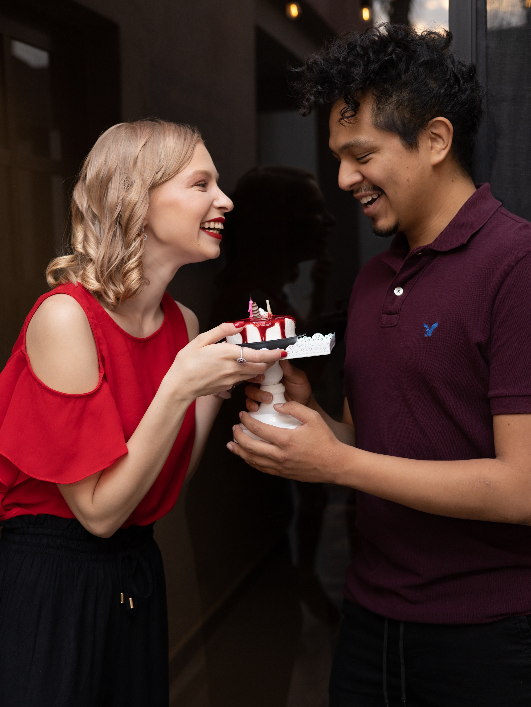 Birthday girl in a red shirt with her boyfriend and with birthday cake