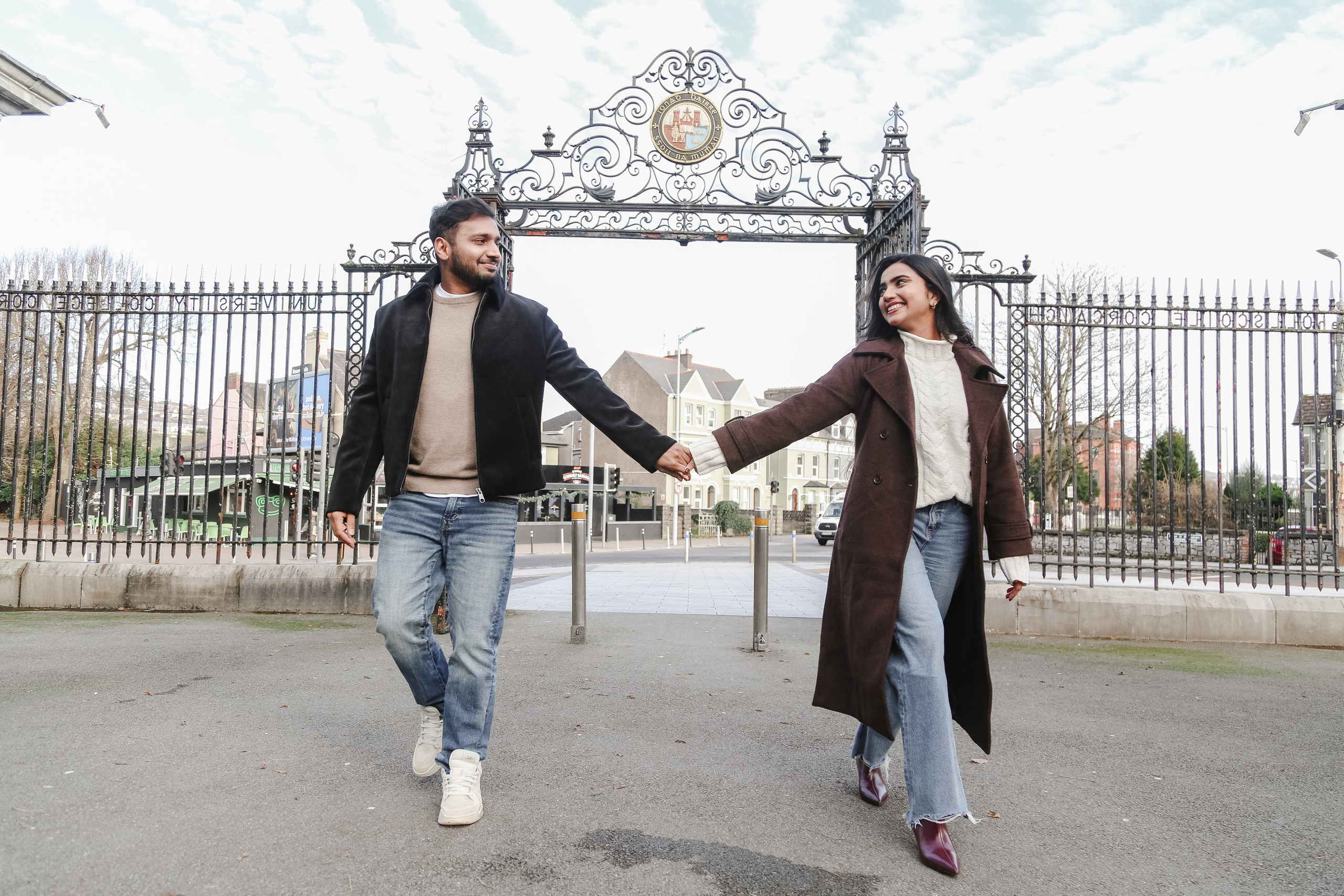 A joyful walk hand in hand, framed by historic gates, capturing movement, balance, and shared direction.