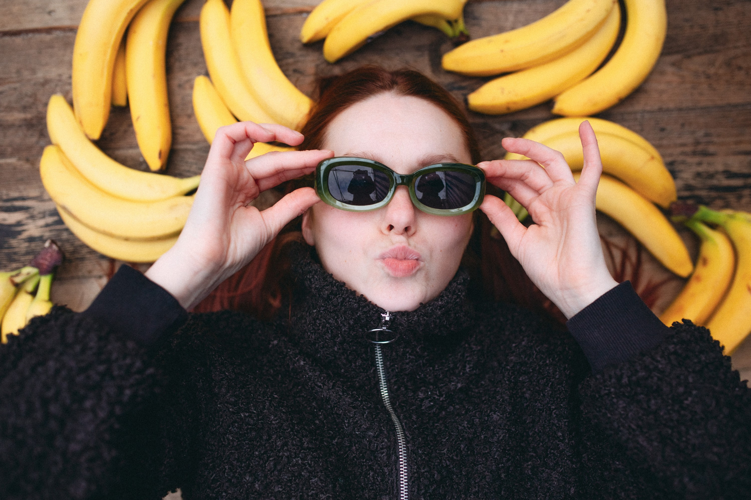Aurinkolaseissa oleva tyttö makaa, ja hänen ympärillään on banaaneja. Lähikuva.