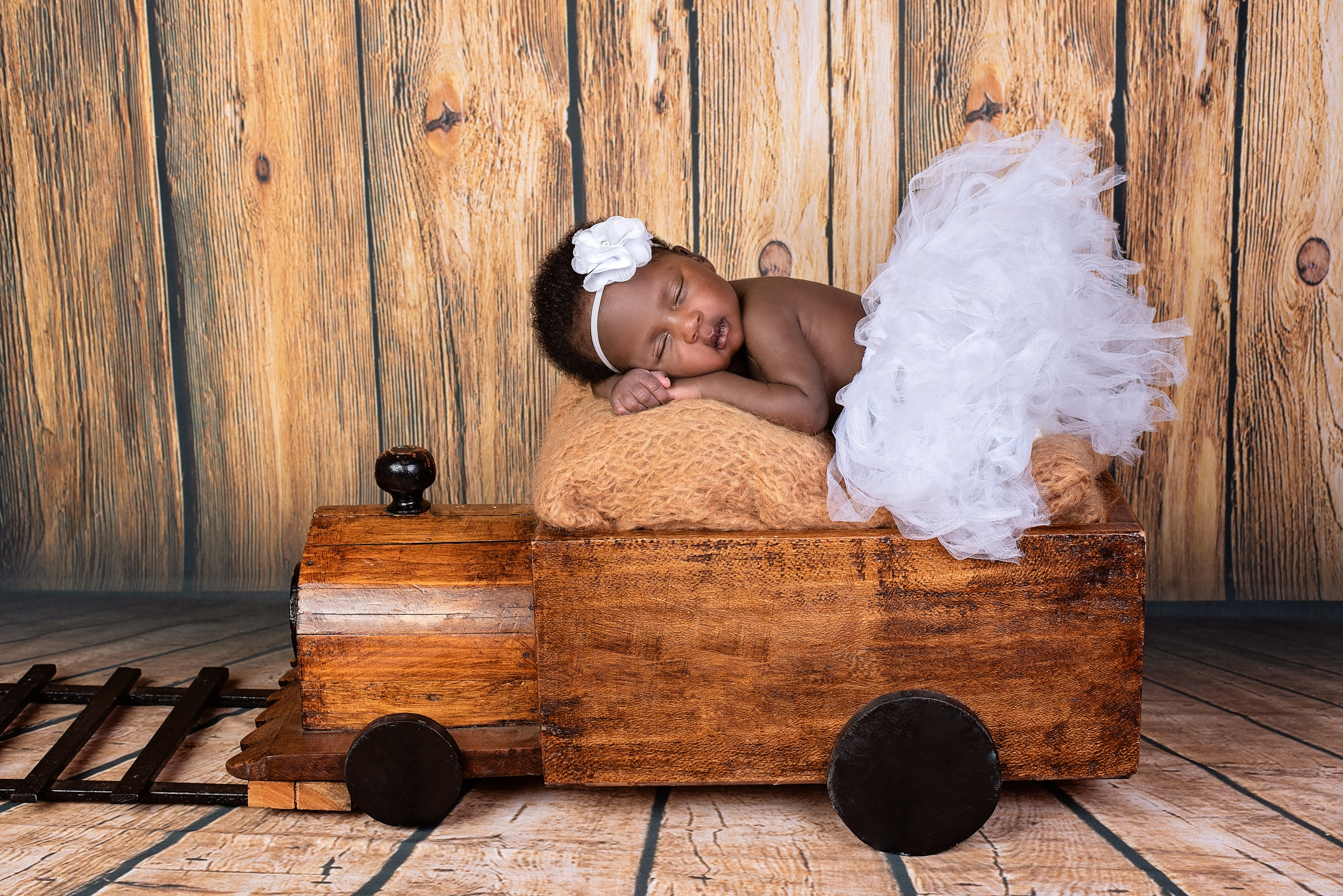Black baby girl 3 weeks newborn photo shoot laying wooden train Mombasa Kenya
