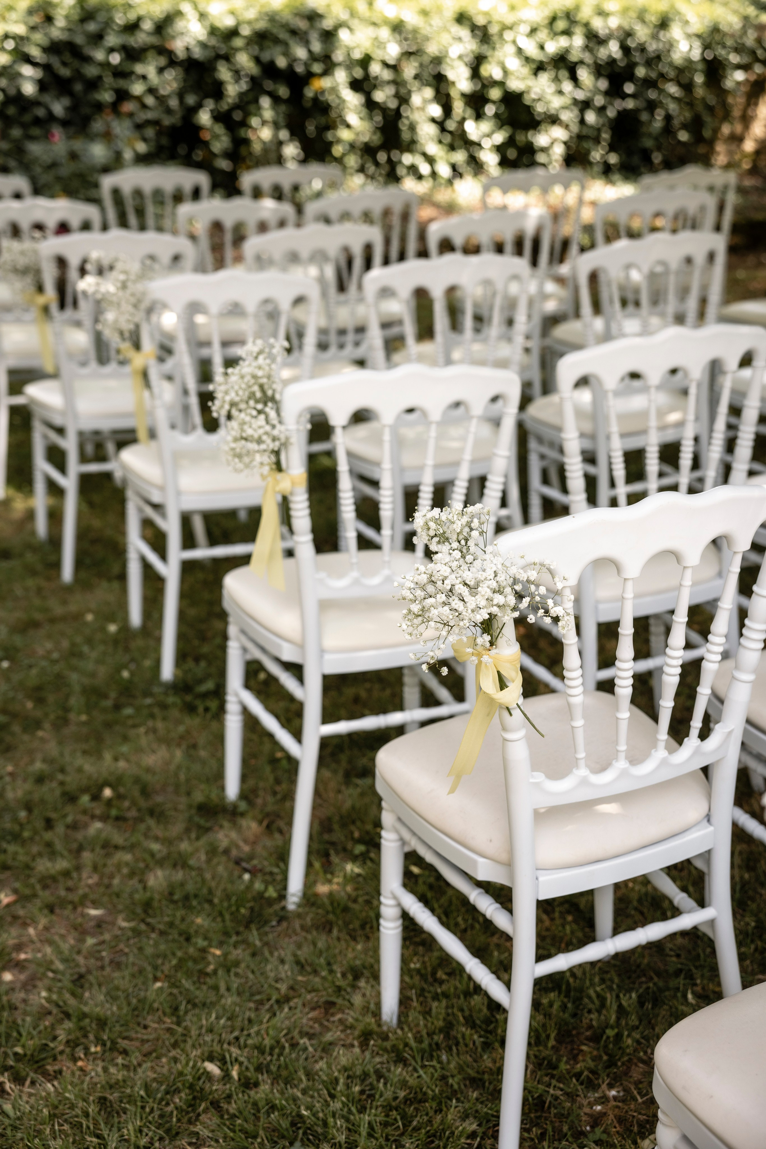 Rows of white chairs set out on the lawn for an outdoor wedding ceremony