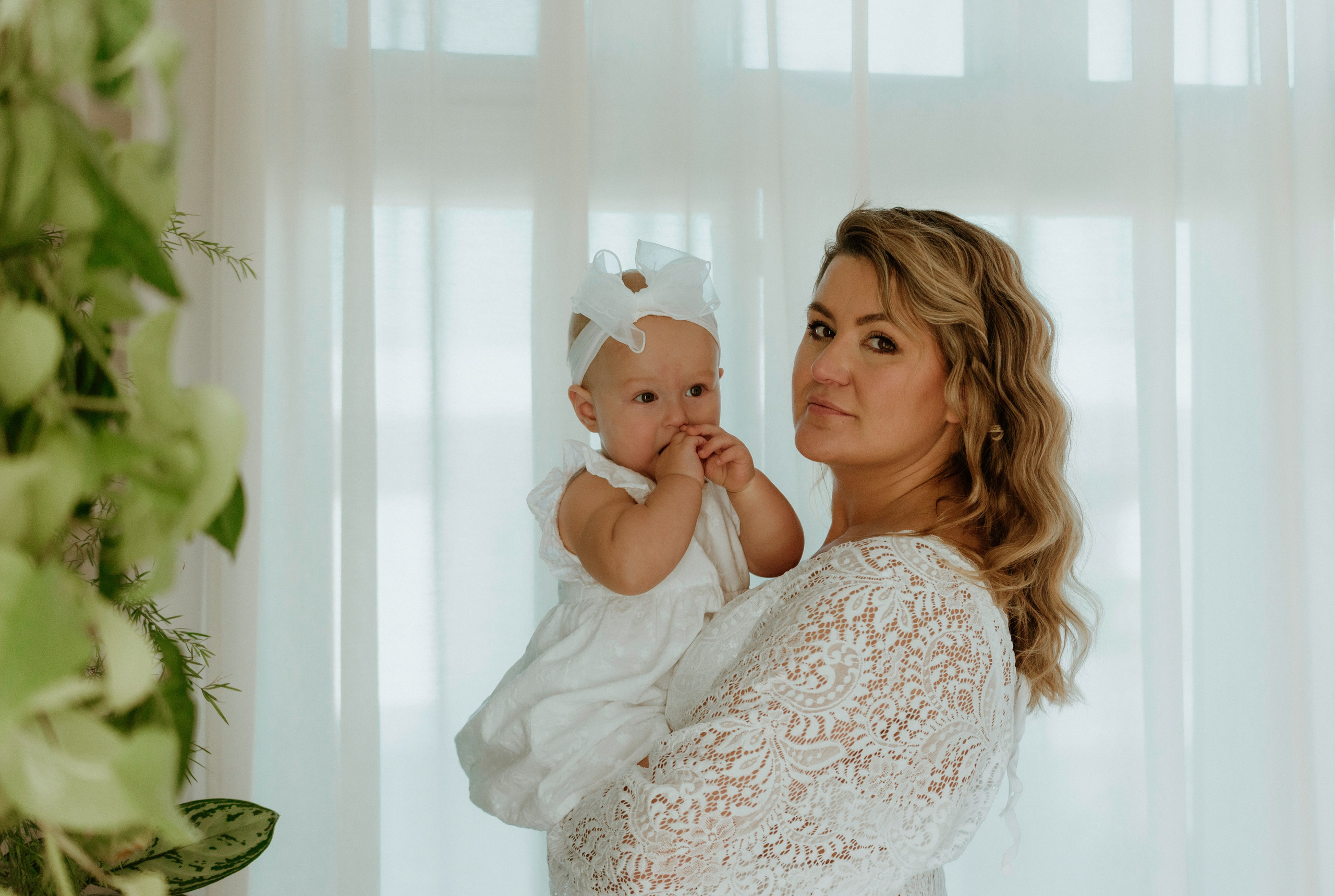 An enchanting outdoor maternity photoshoot at the client's house. The image features a radiant mother and her daughter, both elegantly dressed in white, against the backdrop of their home. The simplicity of their attire and the natural surroundings creates a timeless and intimate atmosphere. Book a personalized outdoor session with MD Studio to capture beautiful moments in the comfort of your own home
