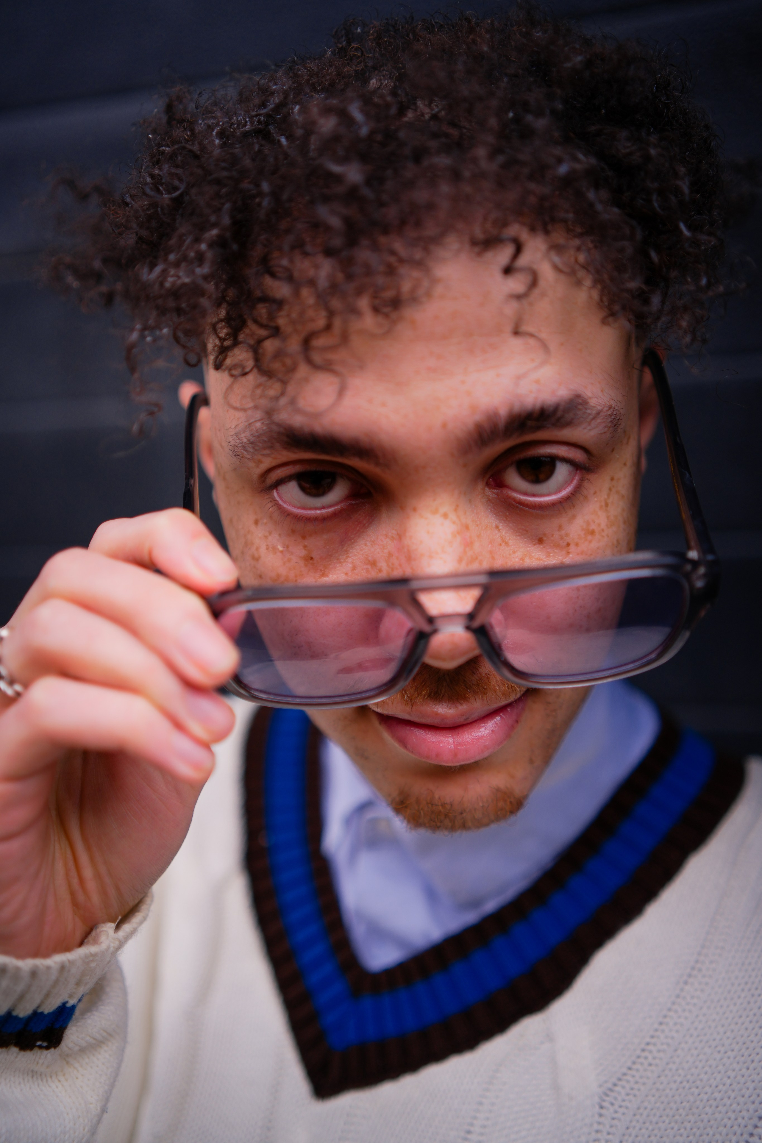 Editorial portrait of a male model adjusting sunglasses, photographed in a fashion-led studio style for creative portrait and brand photography.