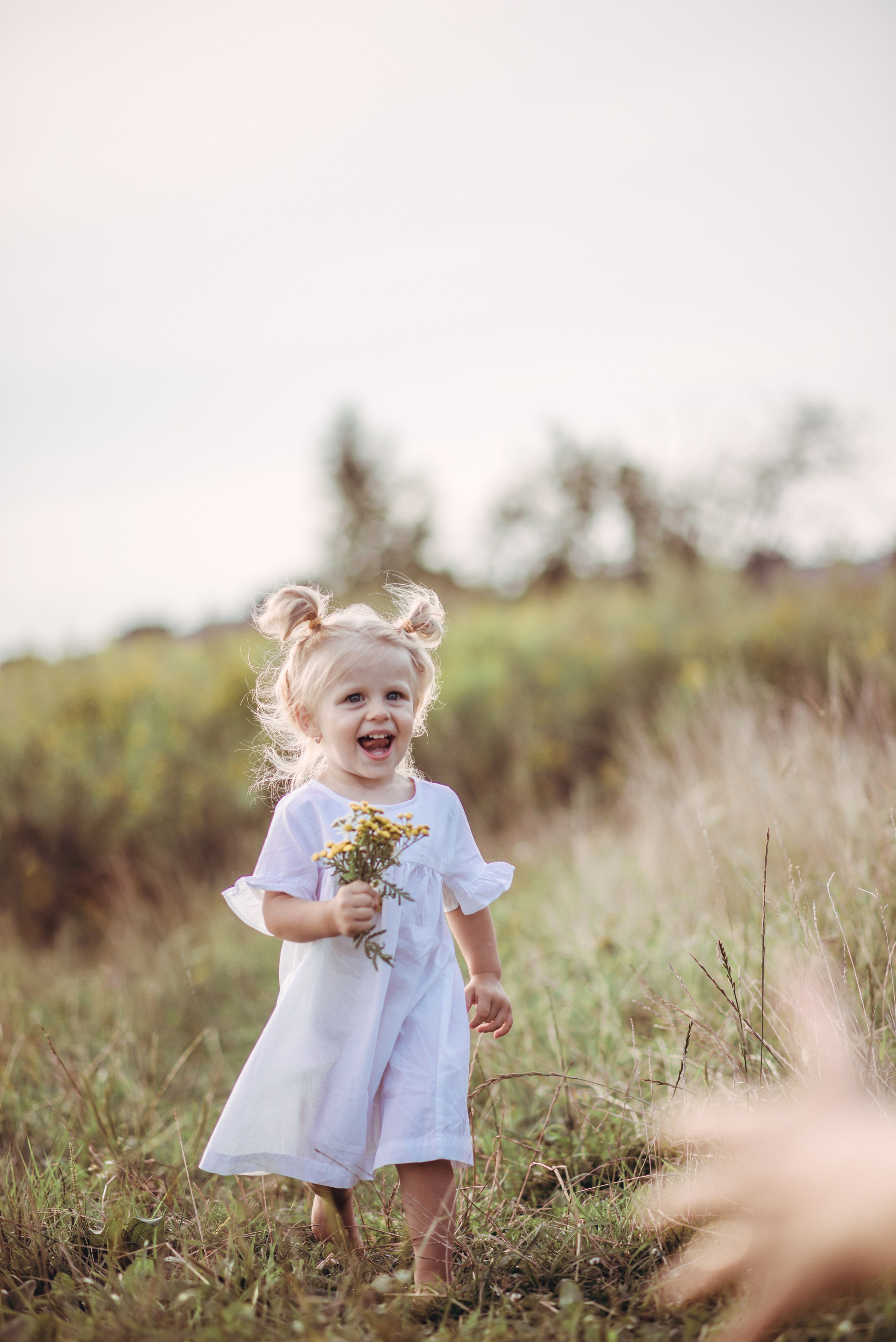 Little girl running in tall grass and smiling