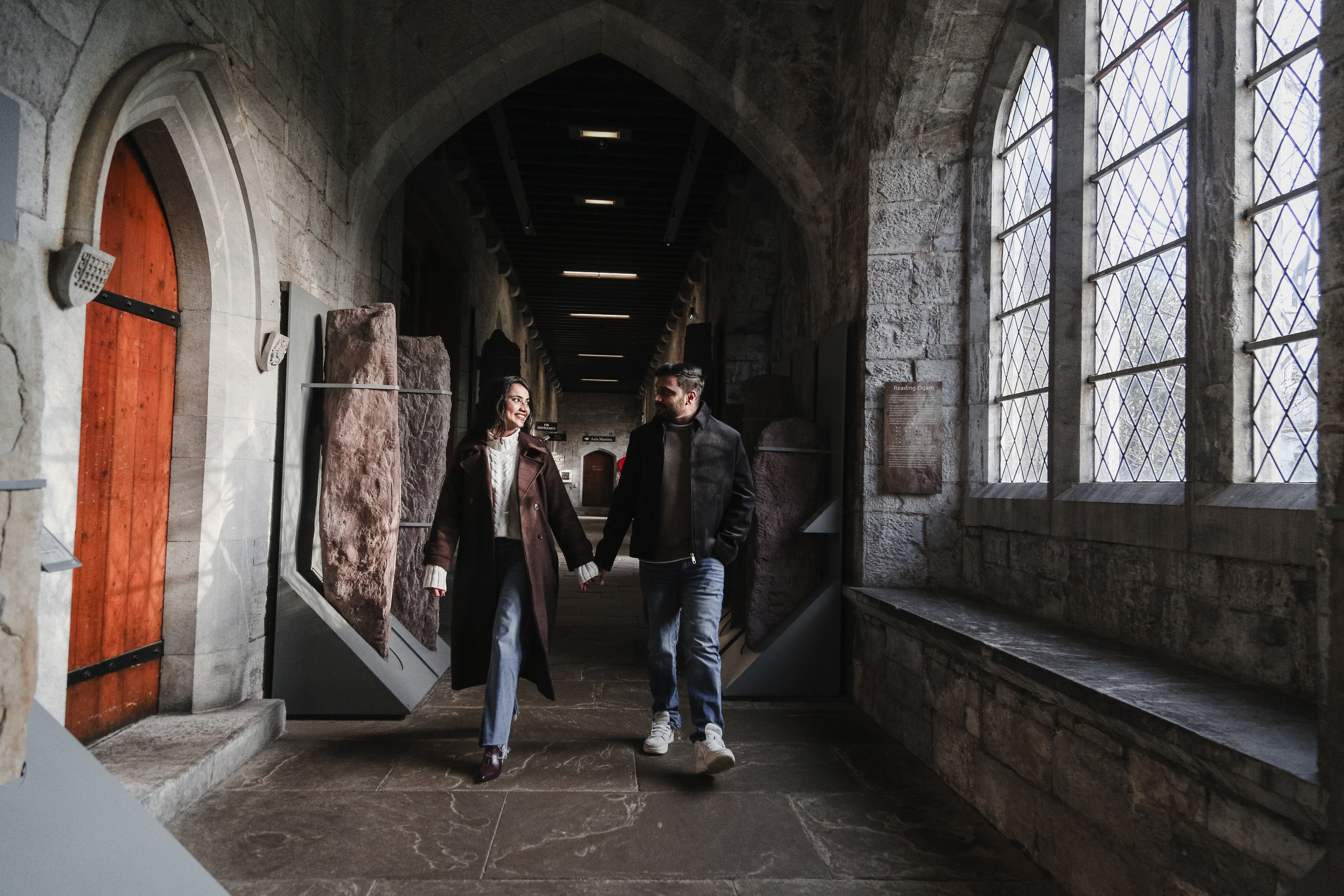 A candid moment in motion, blending history and intimacy as the couple walks naturally through a timeless interior space.