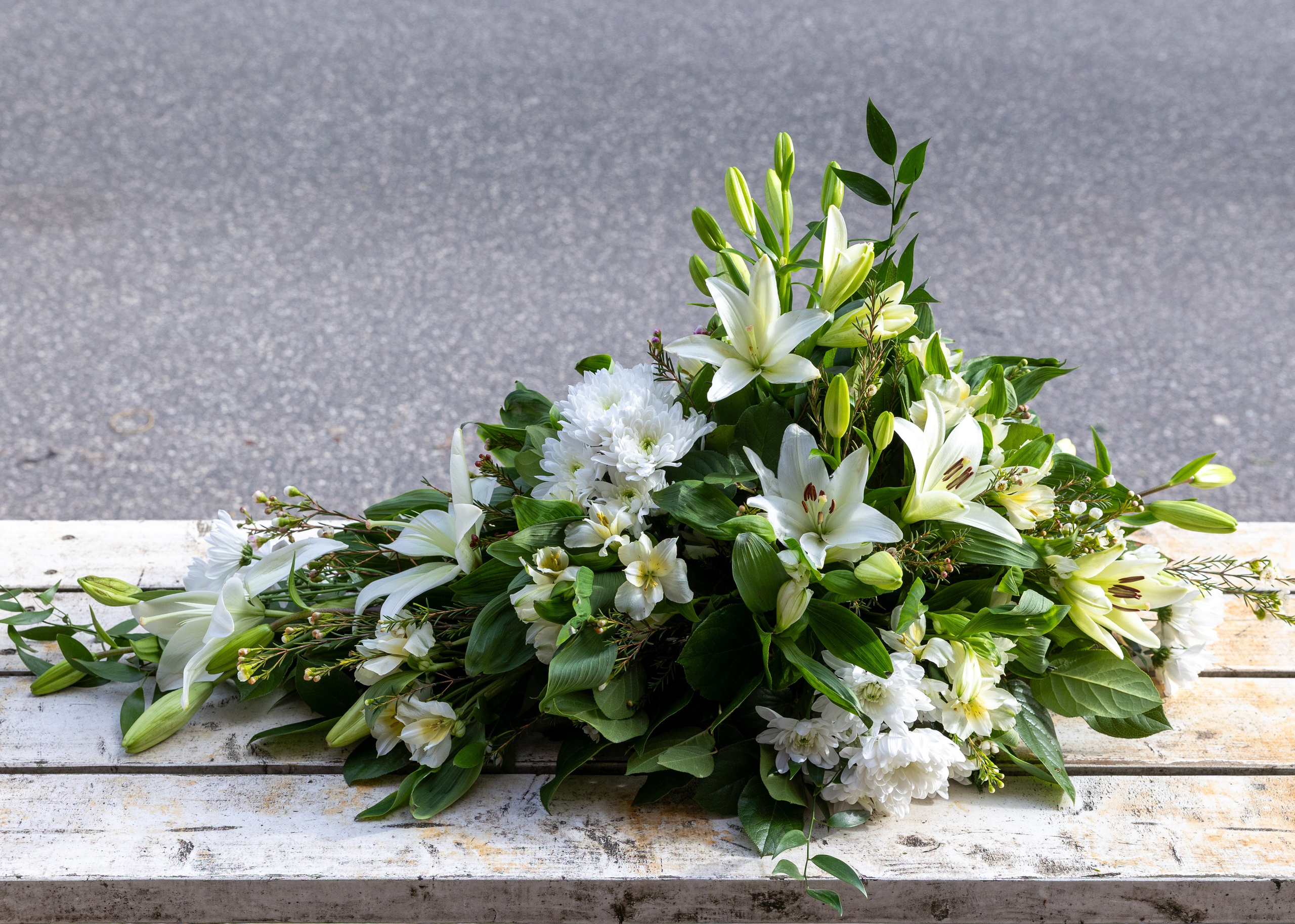 Smuk båredekoration opbygget i oasis med højde og længde på blomsterstilkene. En klassisk udført båredekoration i sæsonens lyse blomster. En elegant og smuk sidste hilsen. 