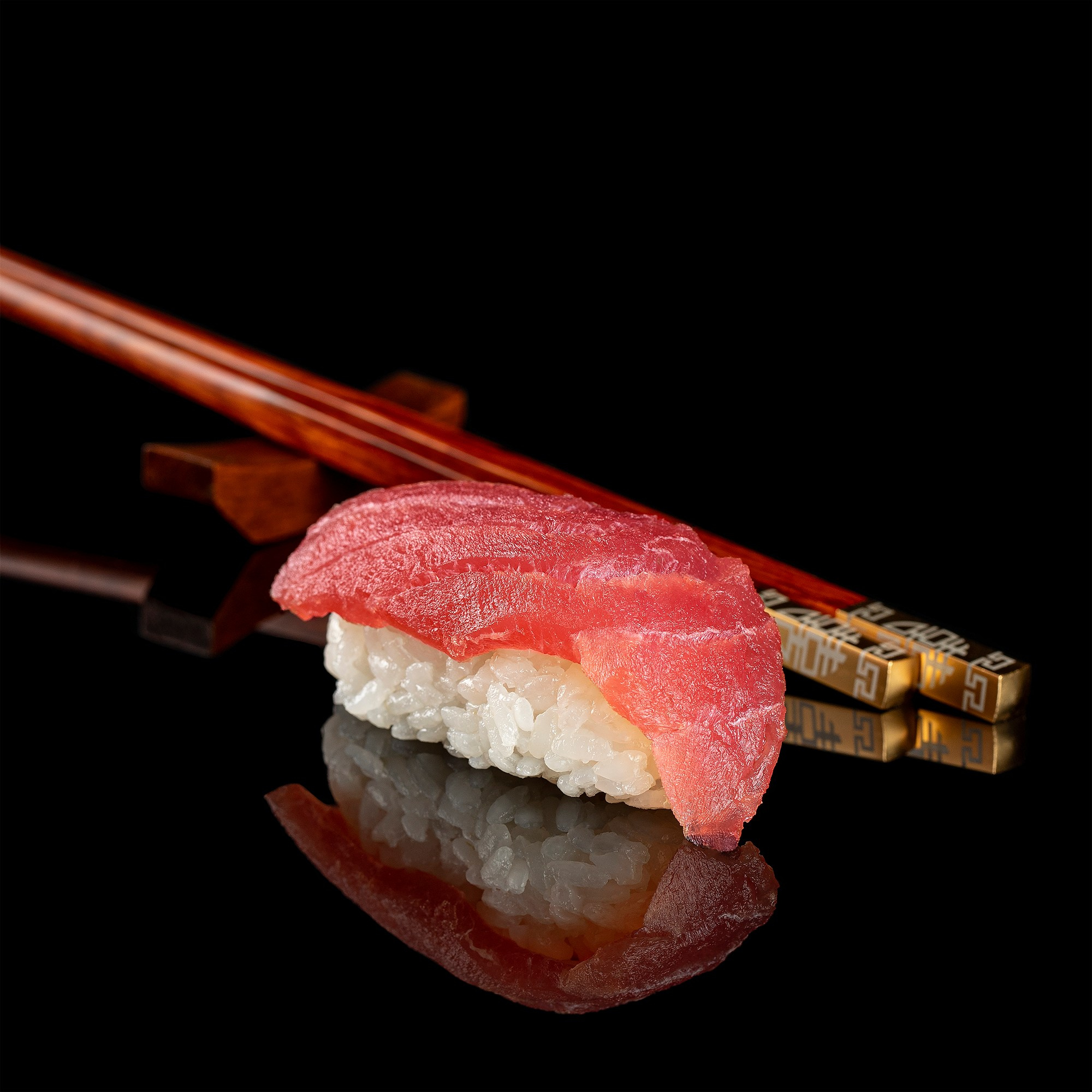 Photographer Roman Djuzev - Sushi Nigiri with tuna with chopsticks on a black acrylic background.