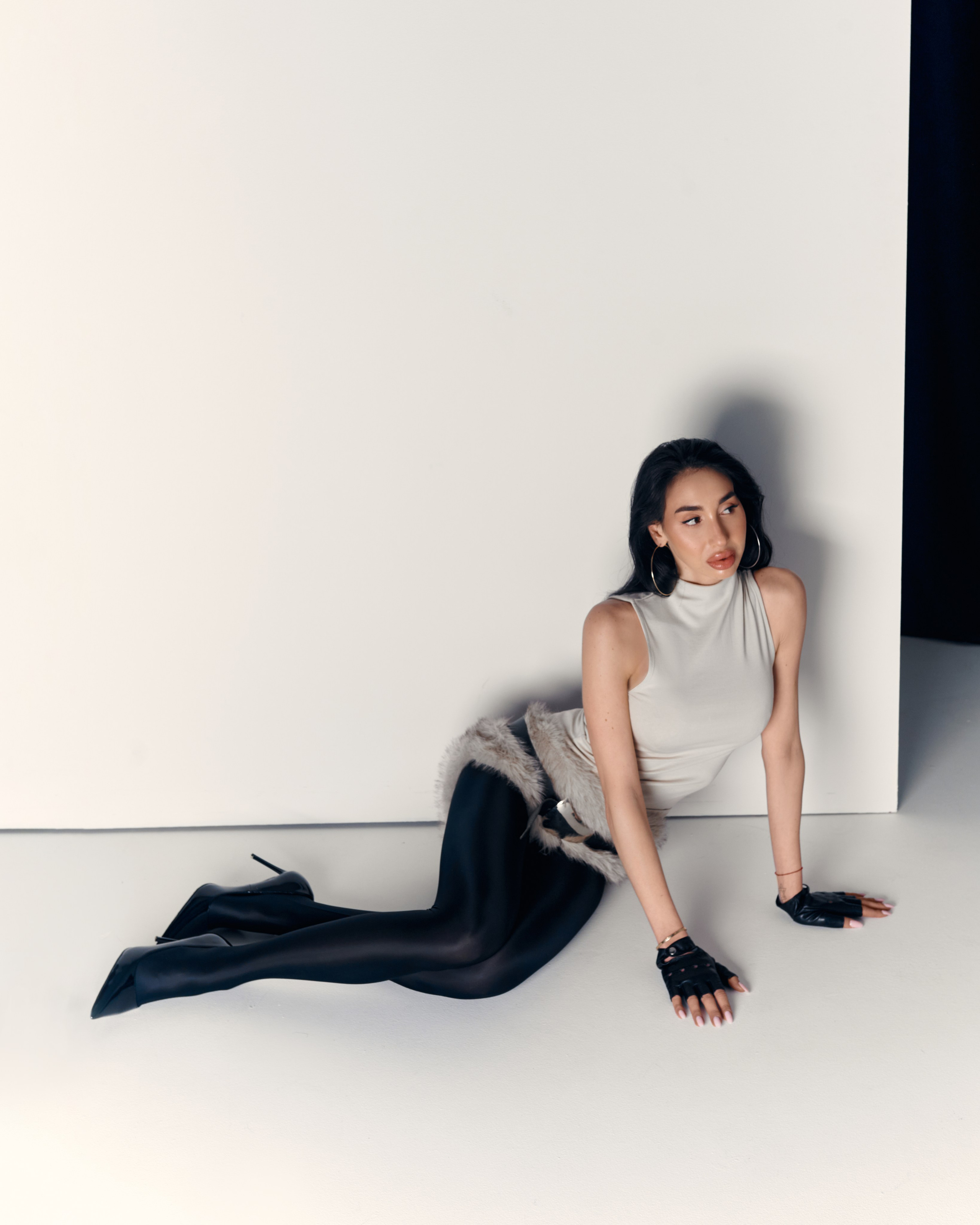 Studio fashion portrait of Ester Rogovaya wearing a fur skirt, minimalist styling and neutral background