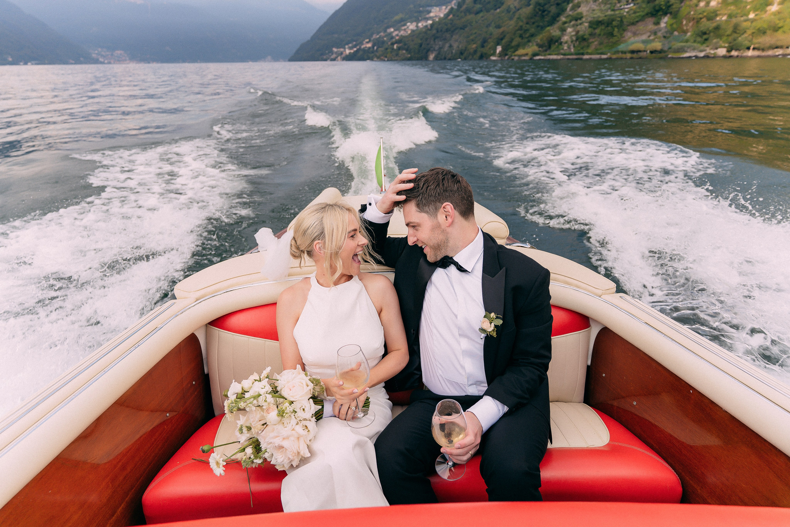 Bride and groom on the boat with a view of Villa Lario, Lake Como, Italy