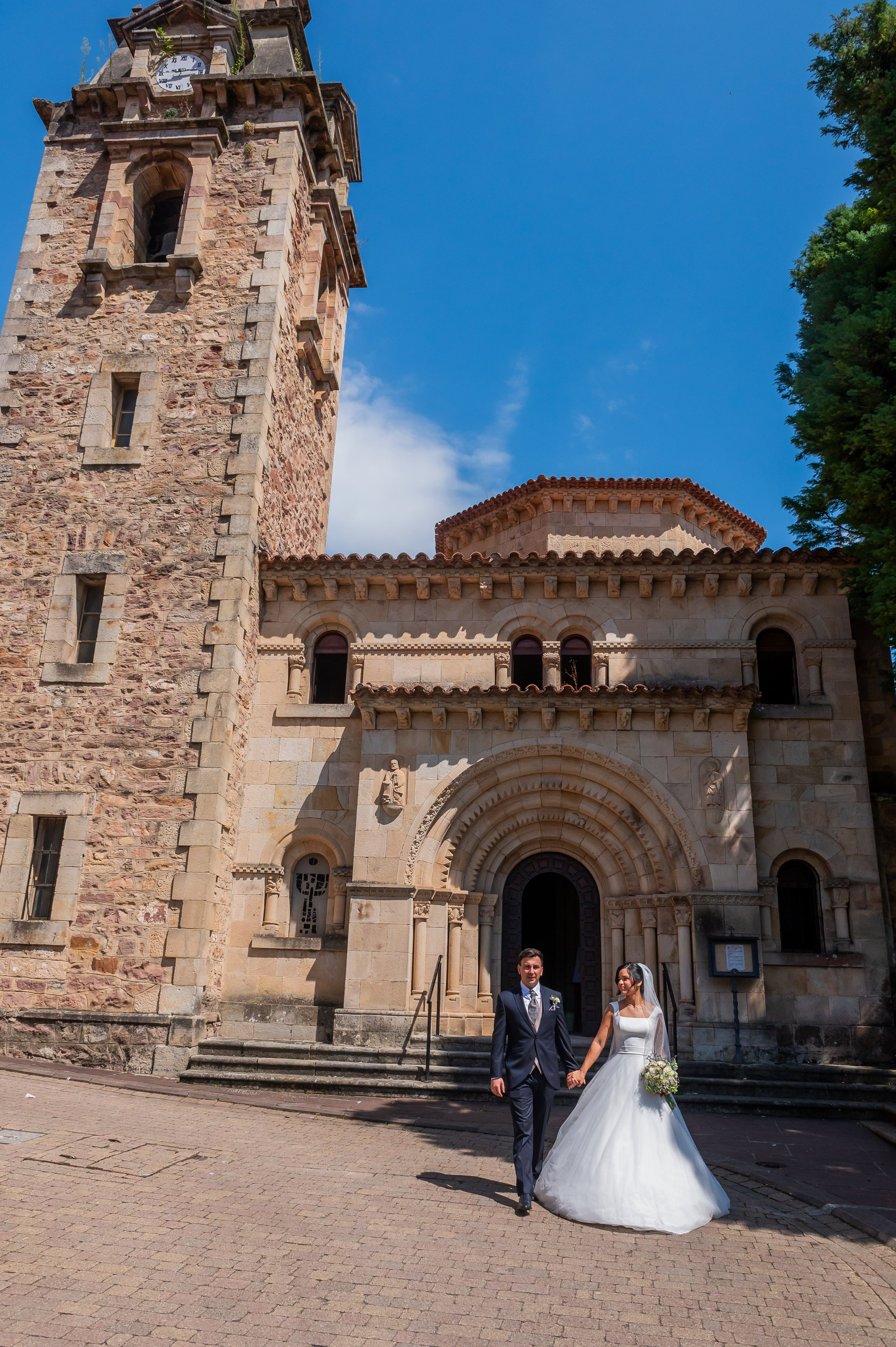 Novios ante la torre de la iglesia · boda en Cantabria