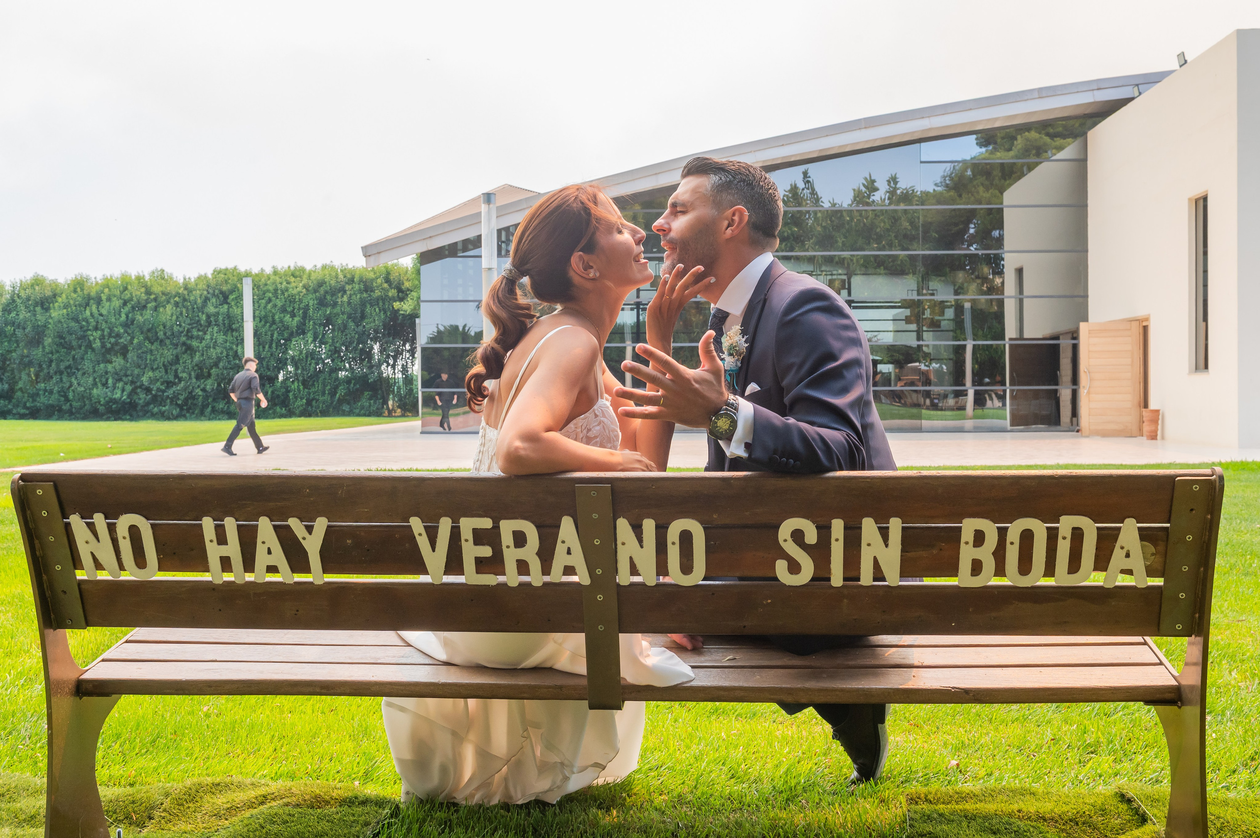 Beso de los novios en el banco del jardín