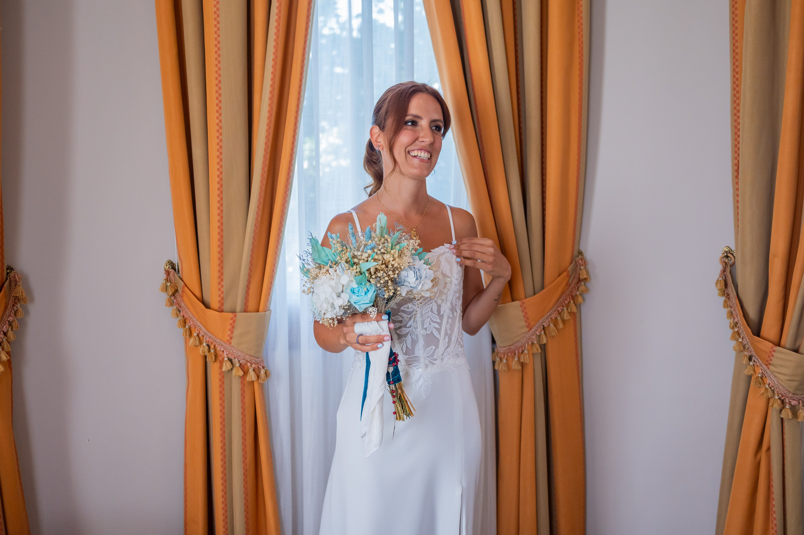 Sara junto a la ventana con su vestido y ramo