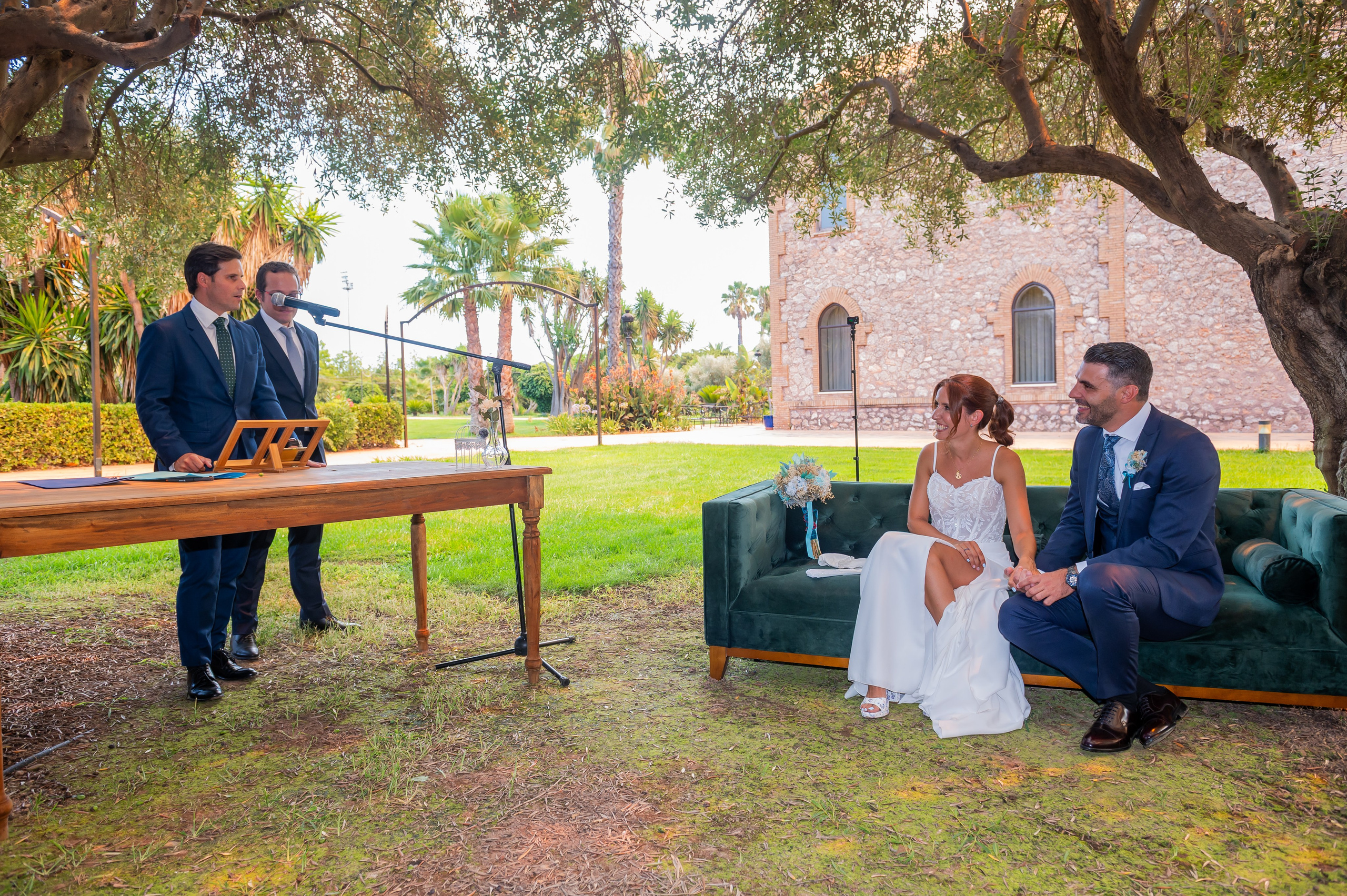Oficiante y novios en la mesa de la ceremonia en el jardín