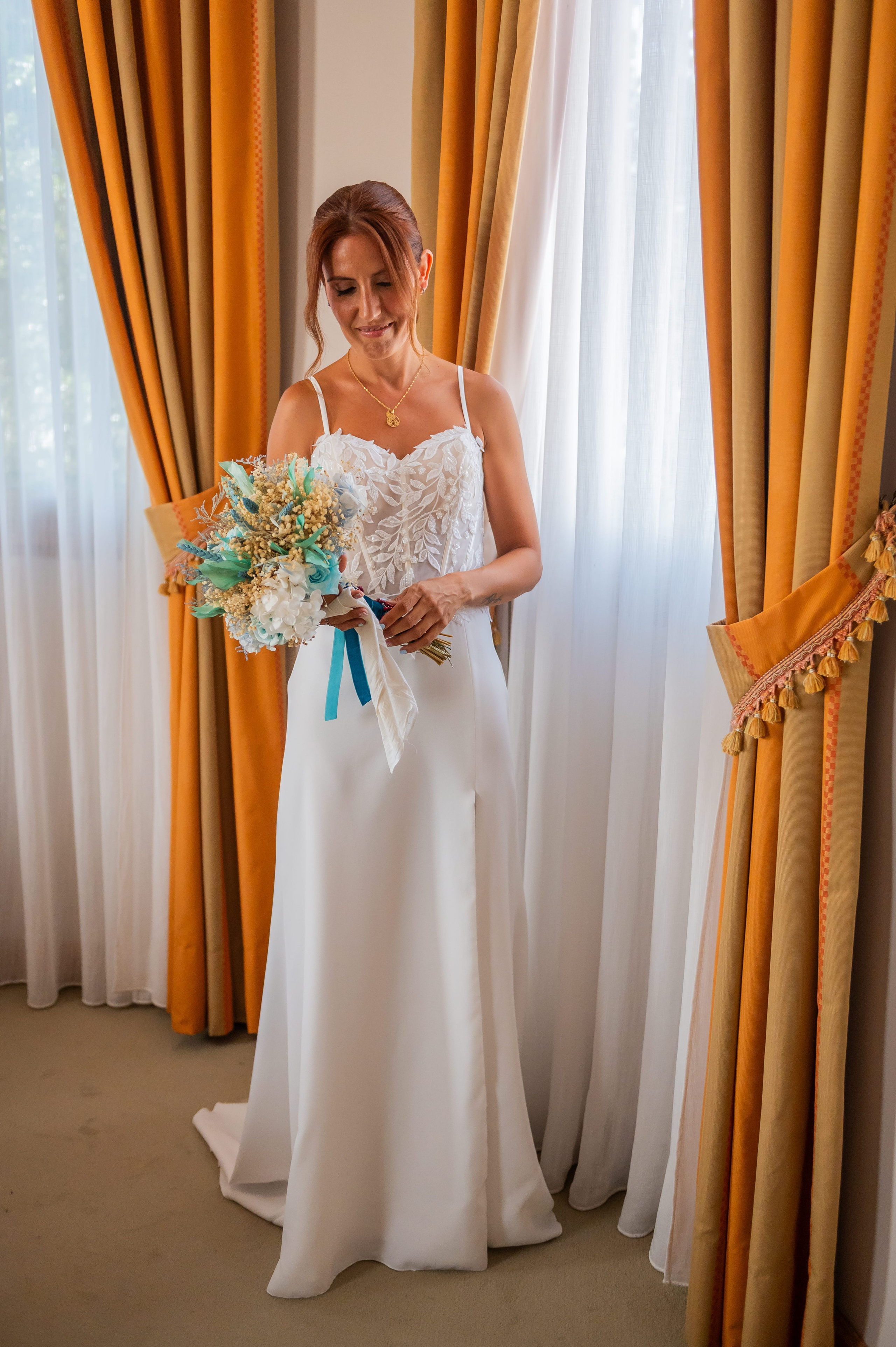 Novia con su ramo de flores secas junto a las cortinas