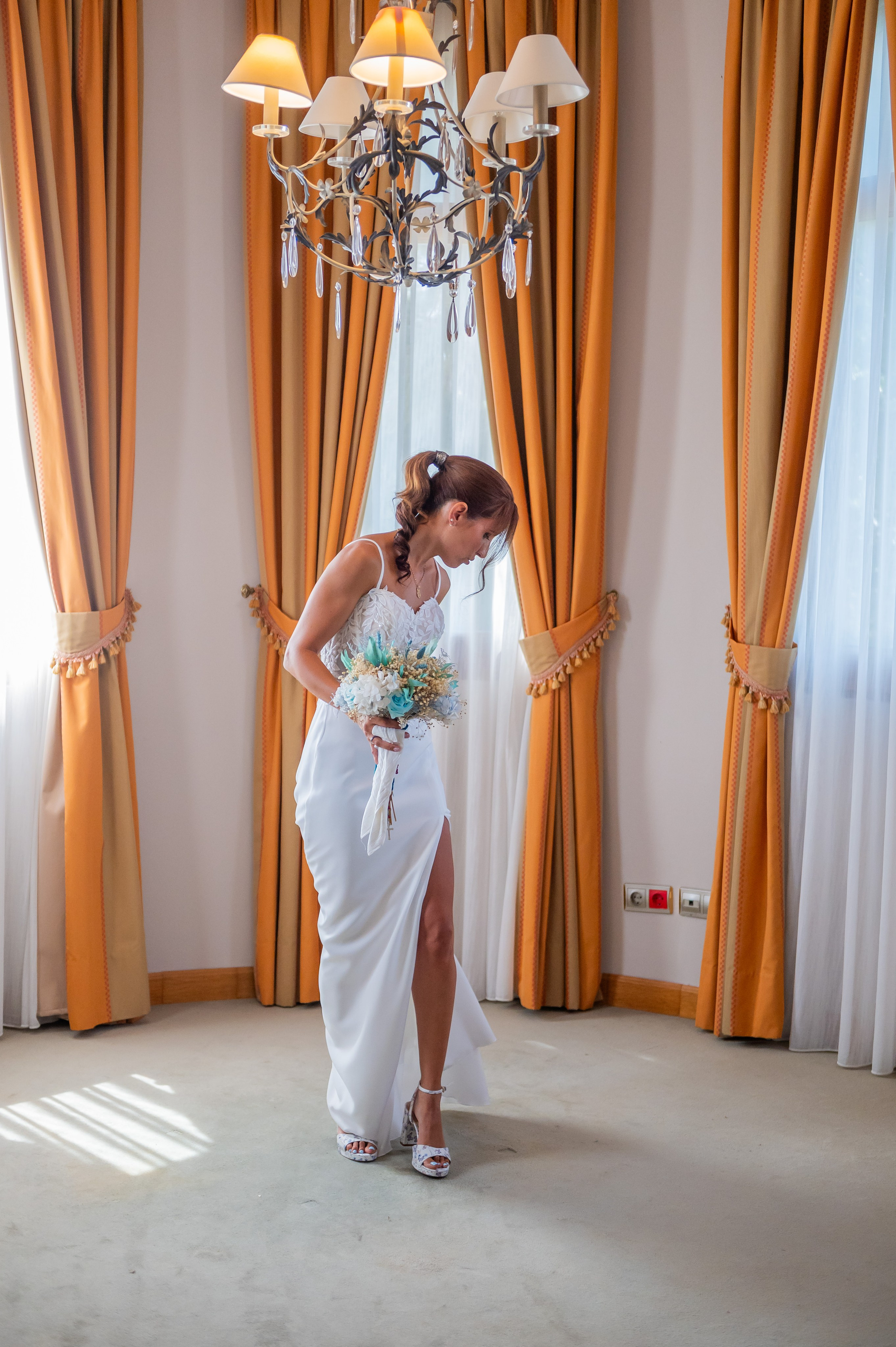 Sara caminando con su vestido bajo la lámpara de araña
