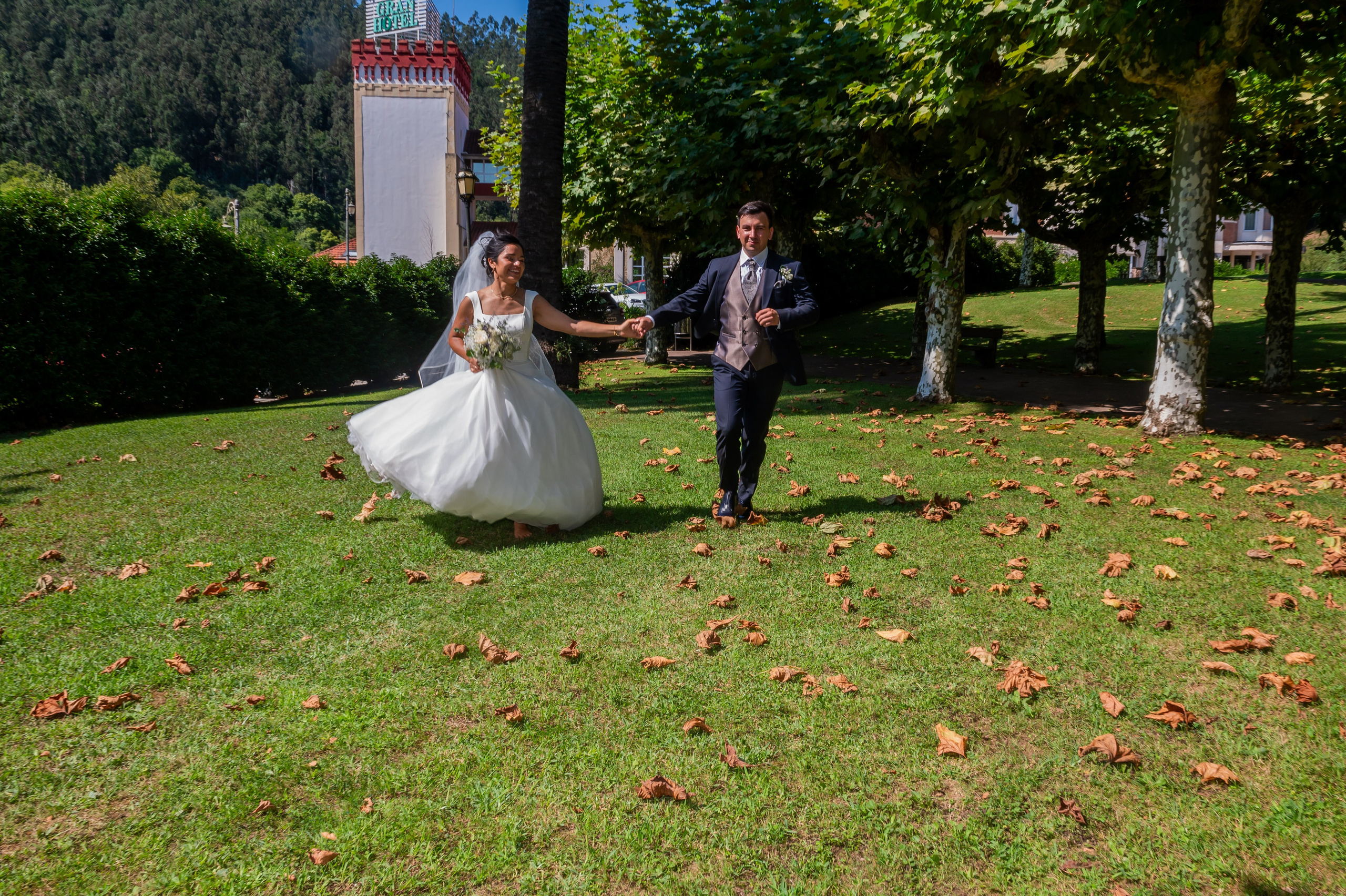 Novios corriendo por el césped del parque del balneario