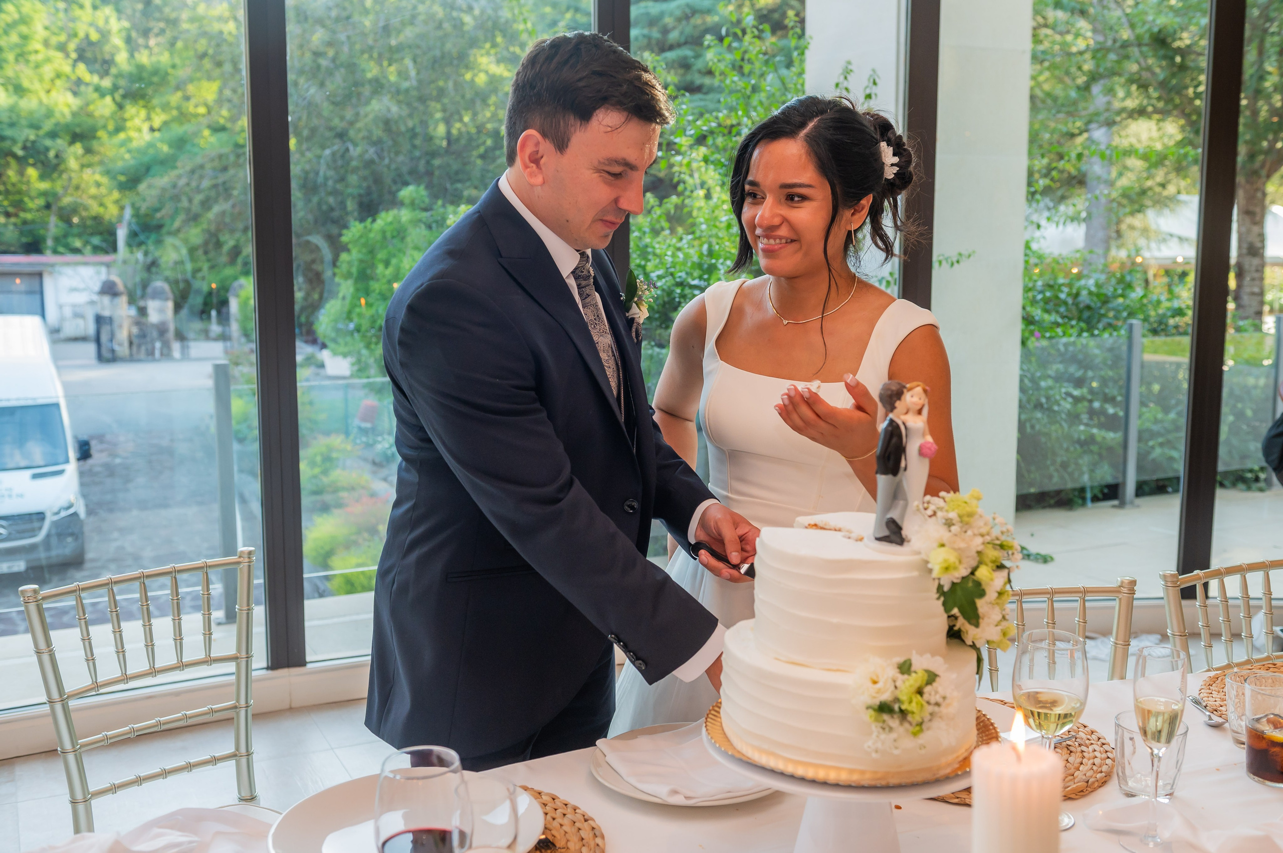 Novios cortando la tarta junto al ventanal