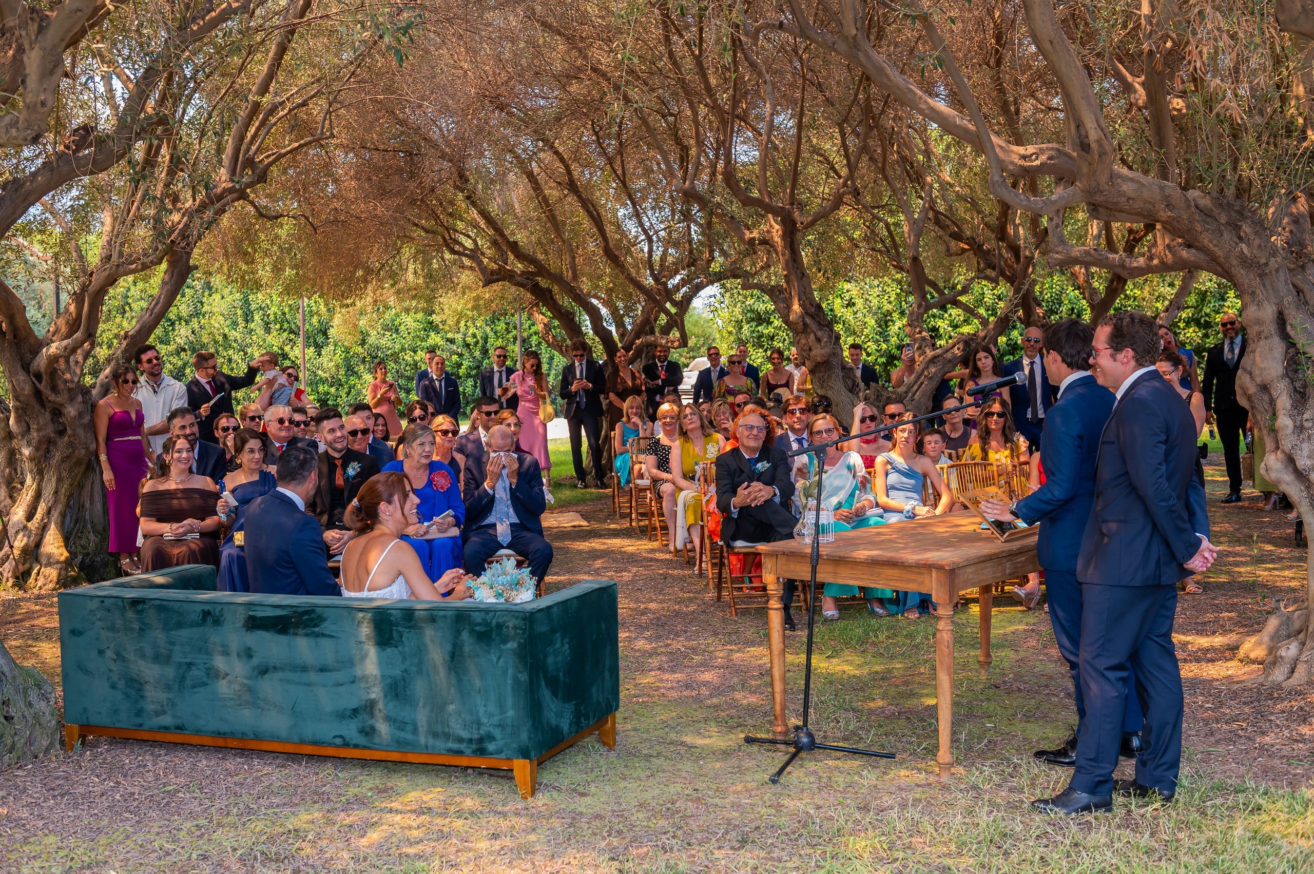 Vista de la ceremonia con invitados bajo los árboles
