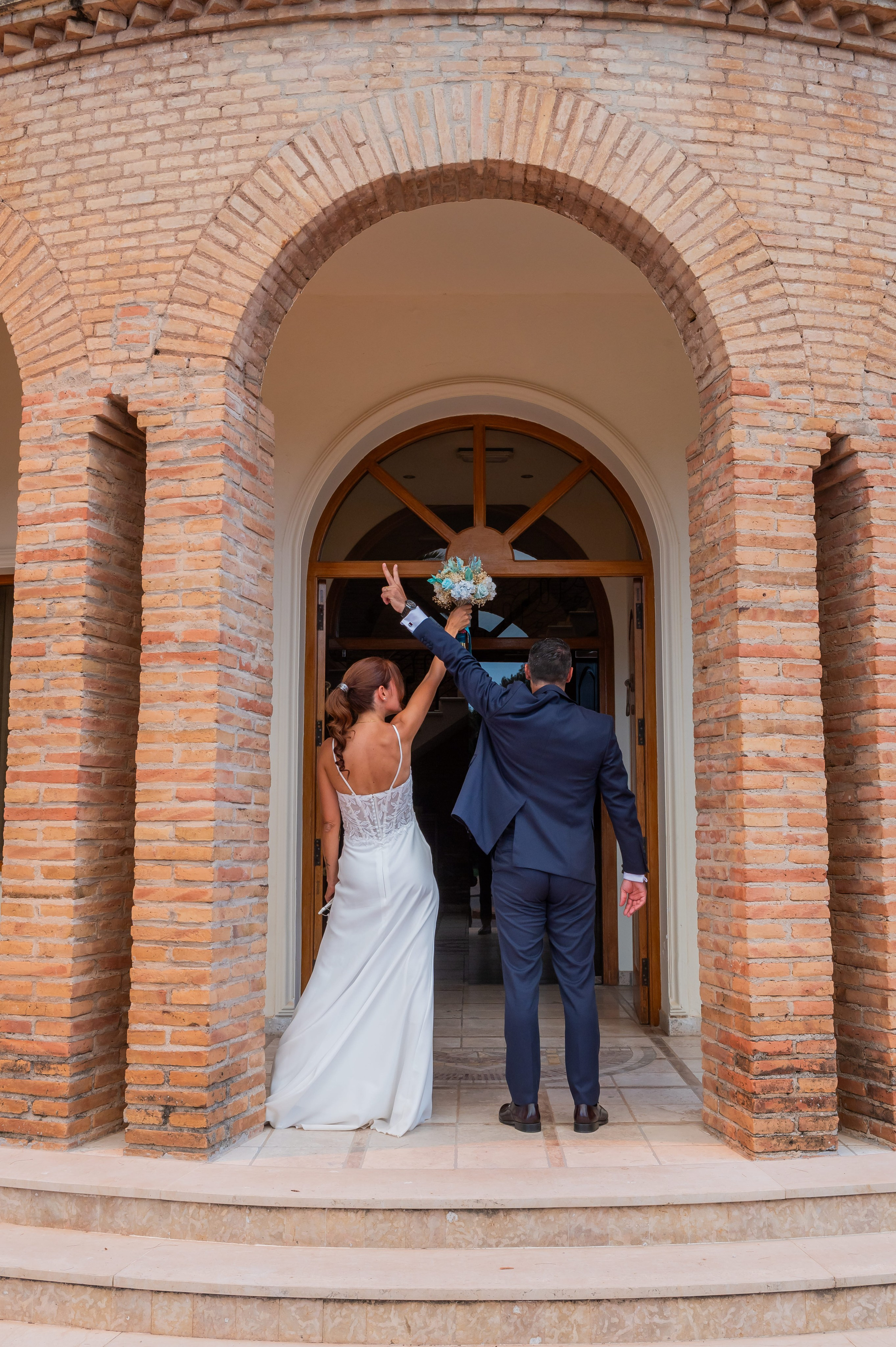 Novios bajo el arco de ladrillo de la entrada