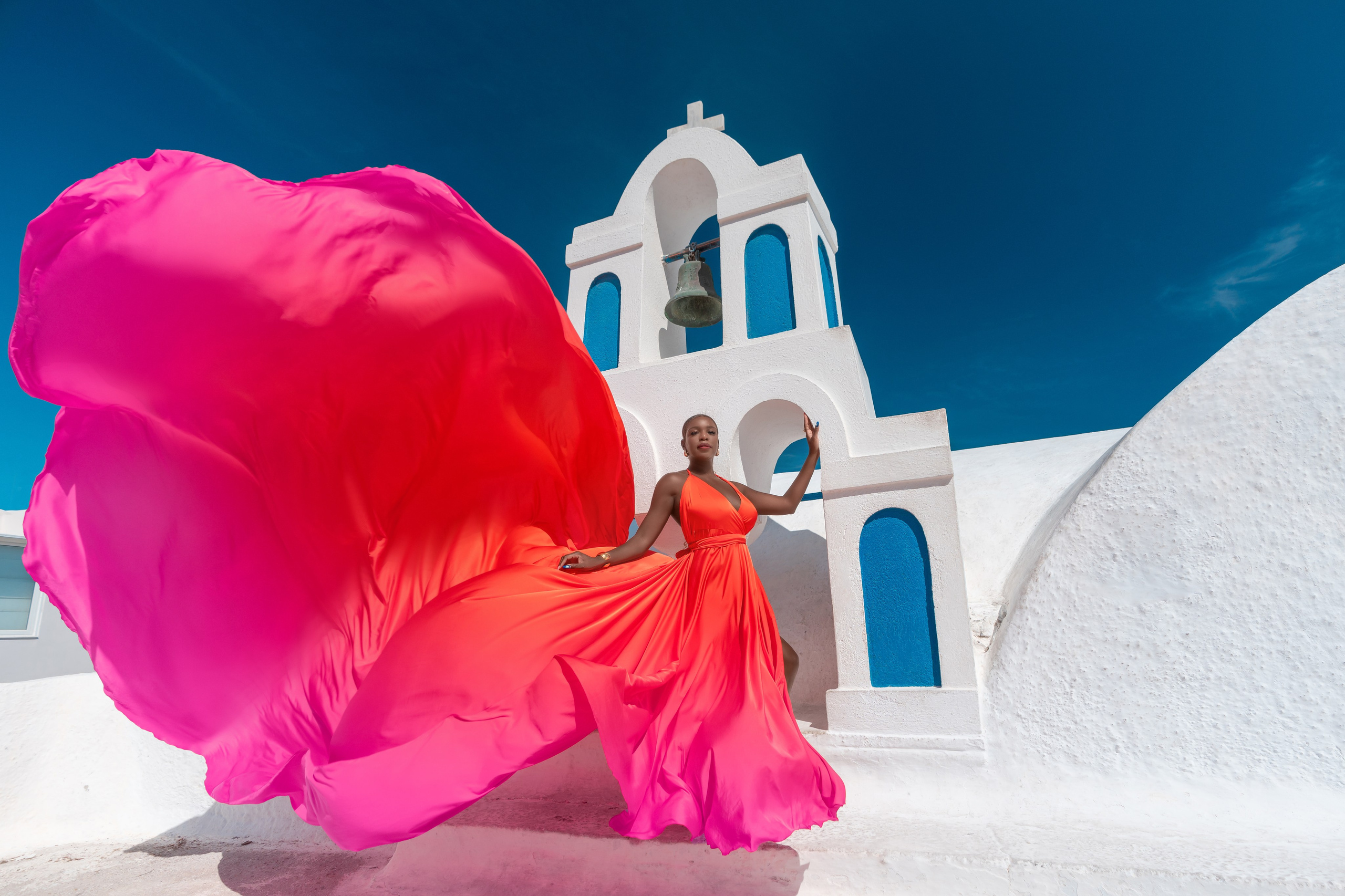 Rent this gorgeous orange-red flying dress for your Santorini photoshoot. Flattering for plus sizes, it delivers elegance, movement, and breathtaking visual impact