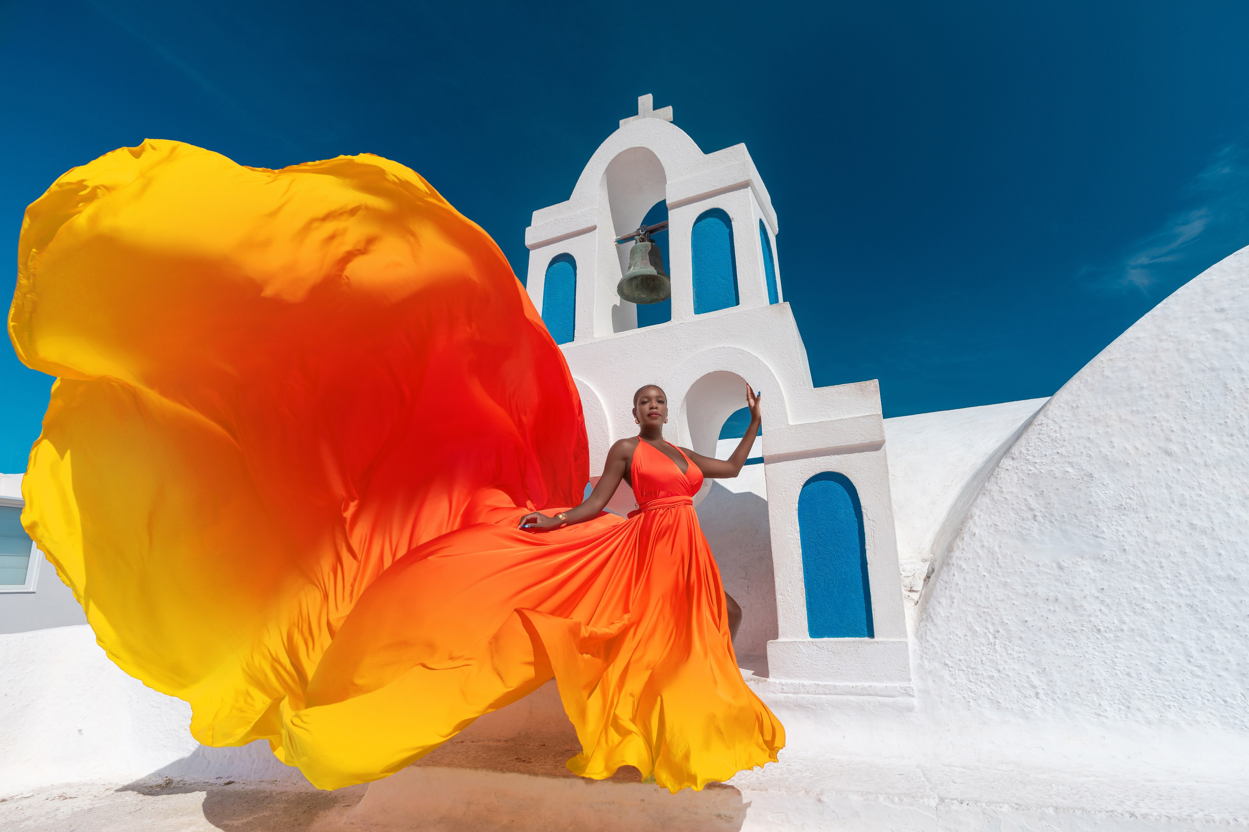 Rent this gorgeous orange-red flying dress for your Santorini photoshoot. Flattering for plus sizes, it delivers elegance, movement, and breathtaking visual impact