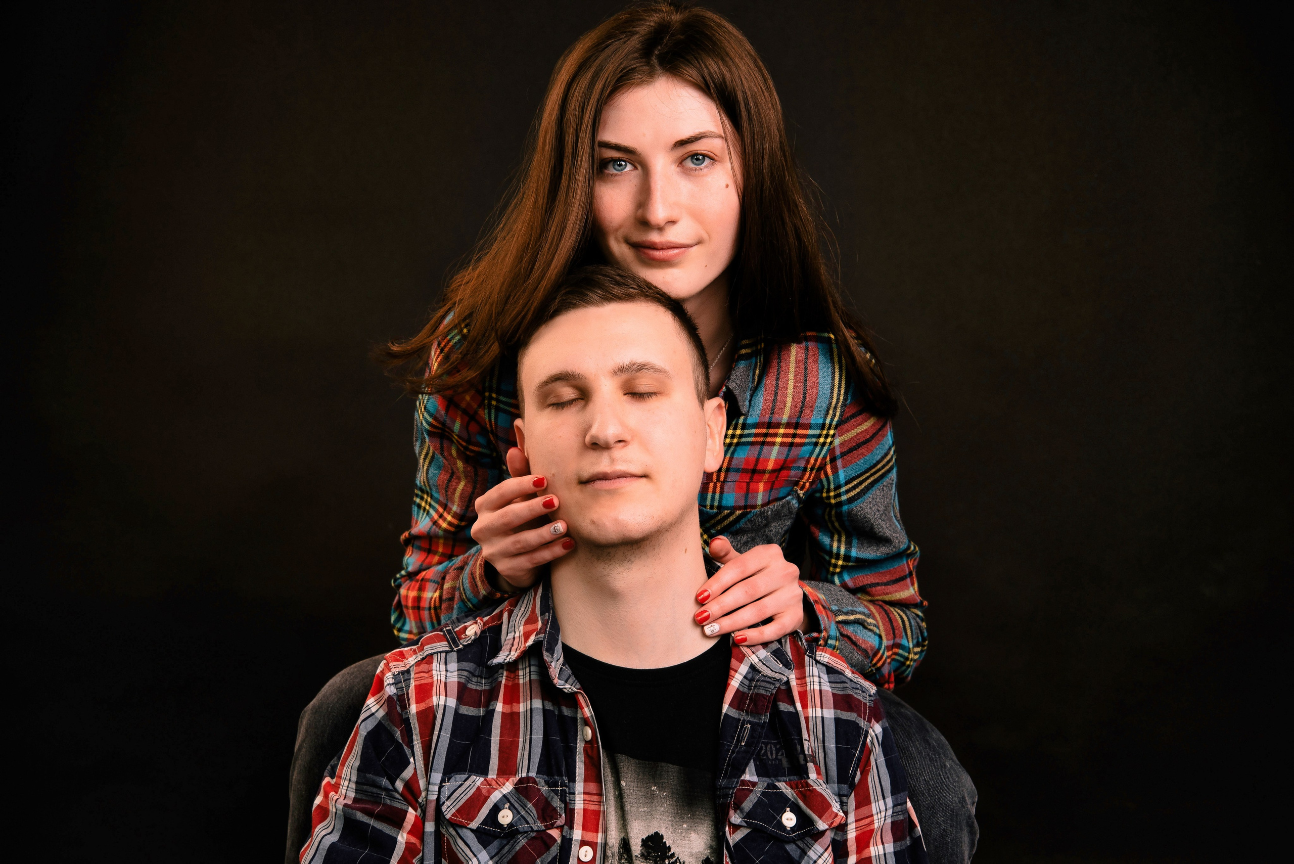 Zwei Personen posieren nah beieinander vor dunklem Hintergrund, modernes emotionales Porträt.