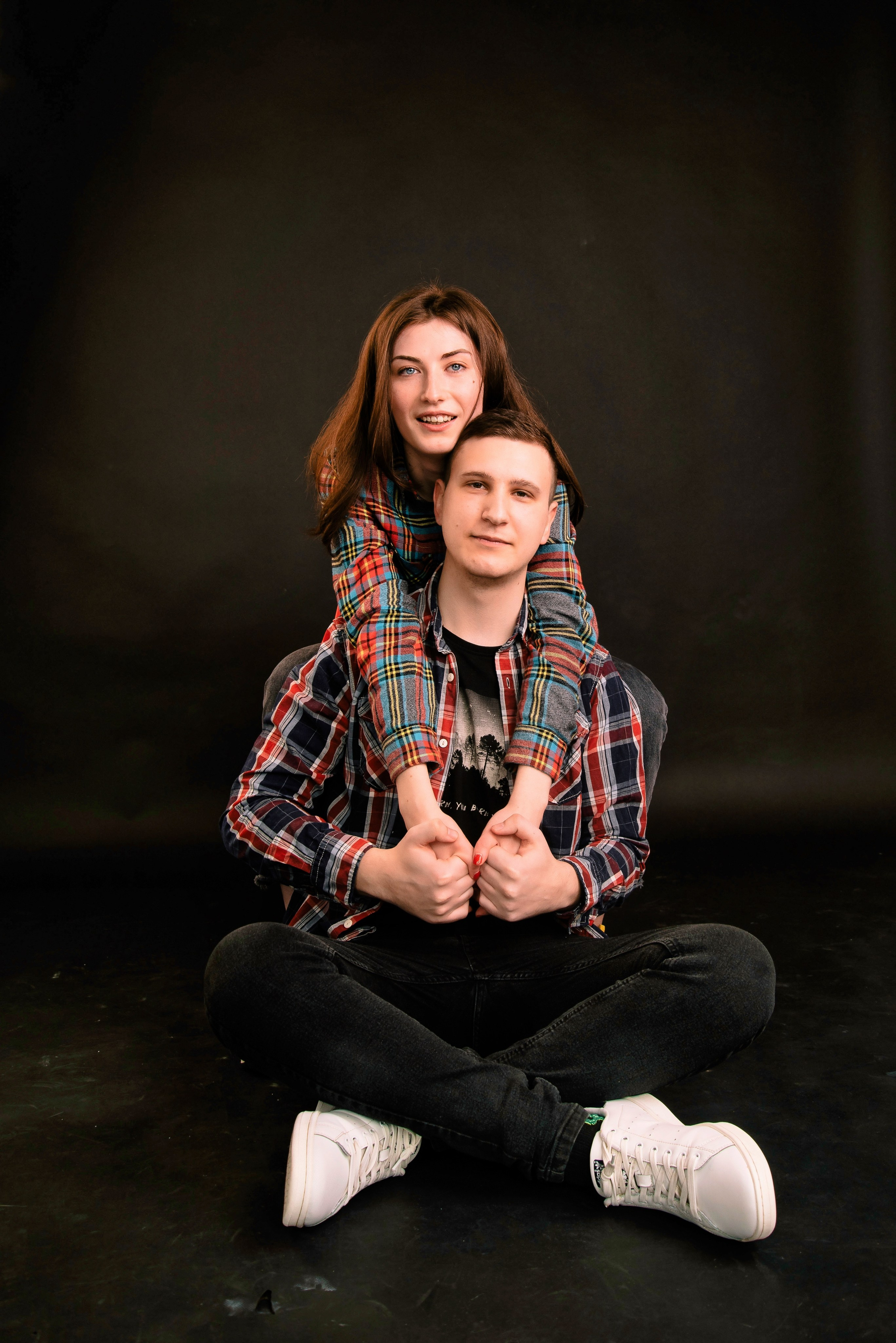 Eine Person steht hinter der anderen und blickt nach vorn, warmes Licht, modernes Paarporträt.