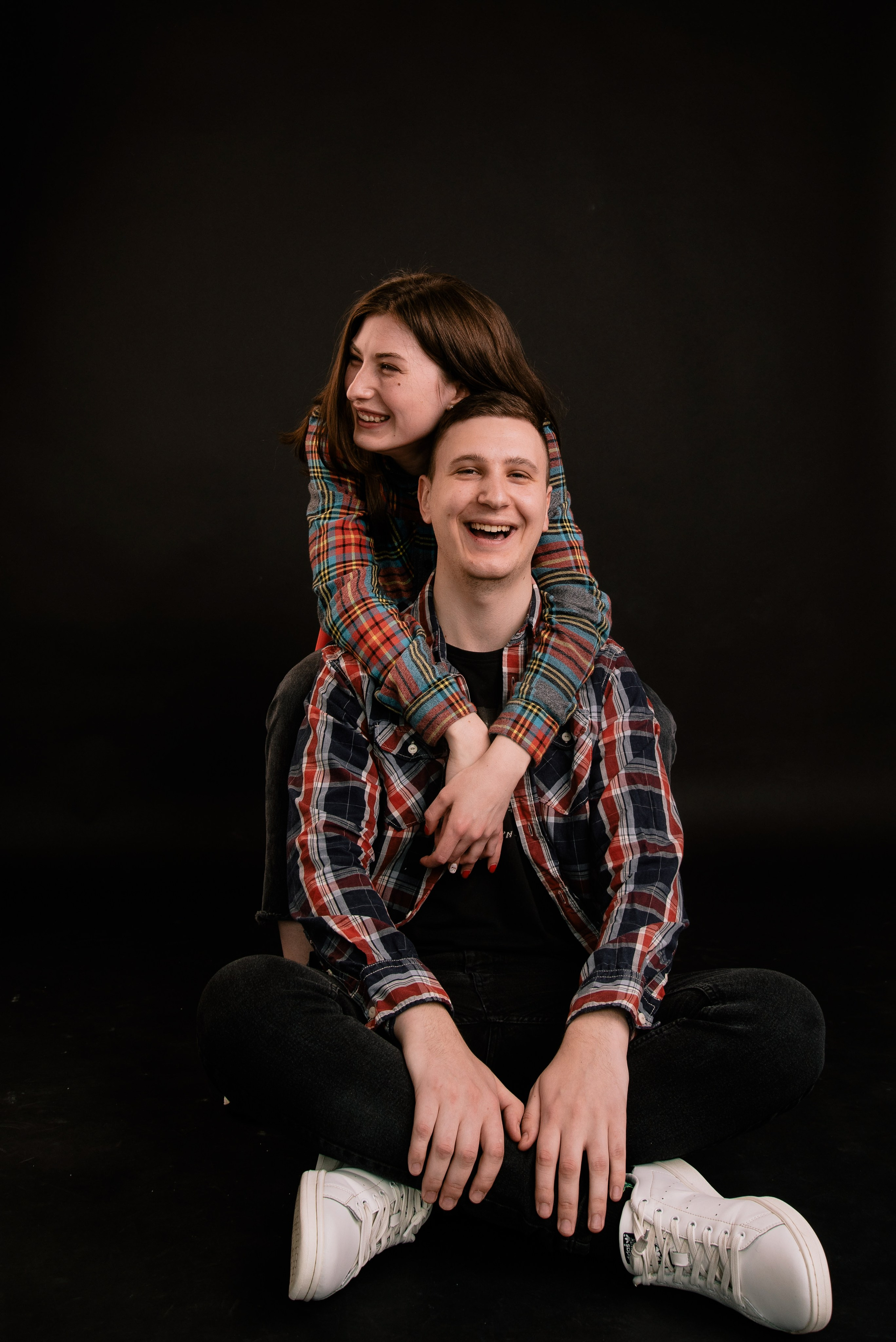 Eine Person sitzt auf dem Boden im Studio und blickt ruhig in die Kamera, warmes Licht und weiches Porträt.