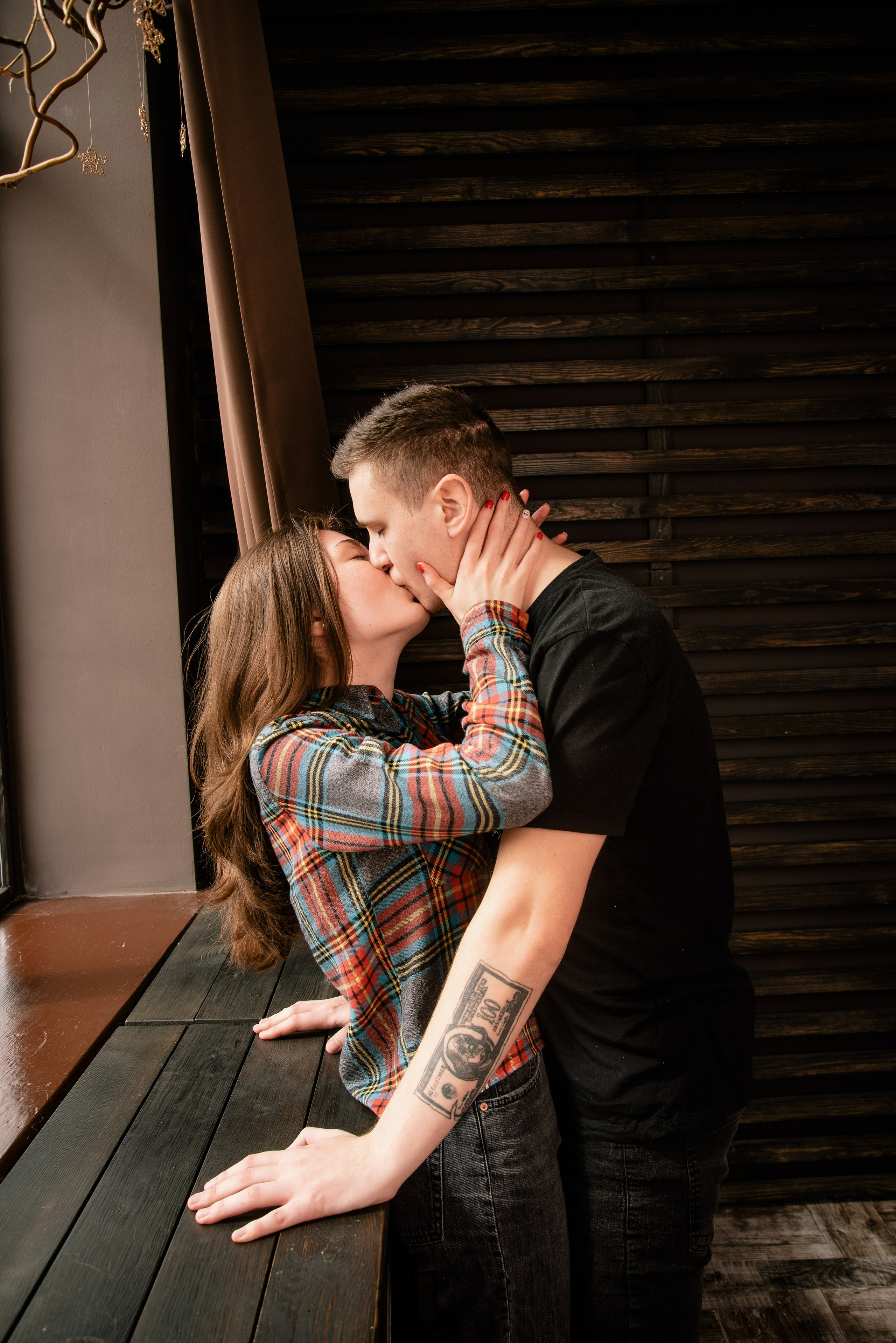 Ein Paar sitzt und steht nah beieinander am Fenster, weiches Licht und ruhige, intime Atmosphäre.