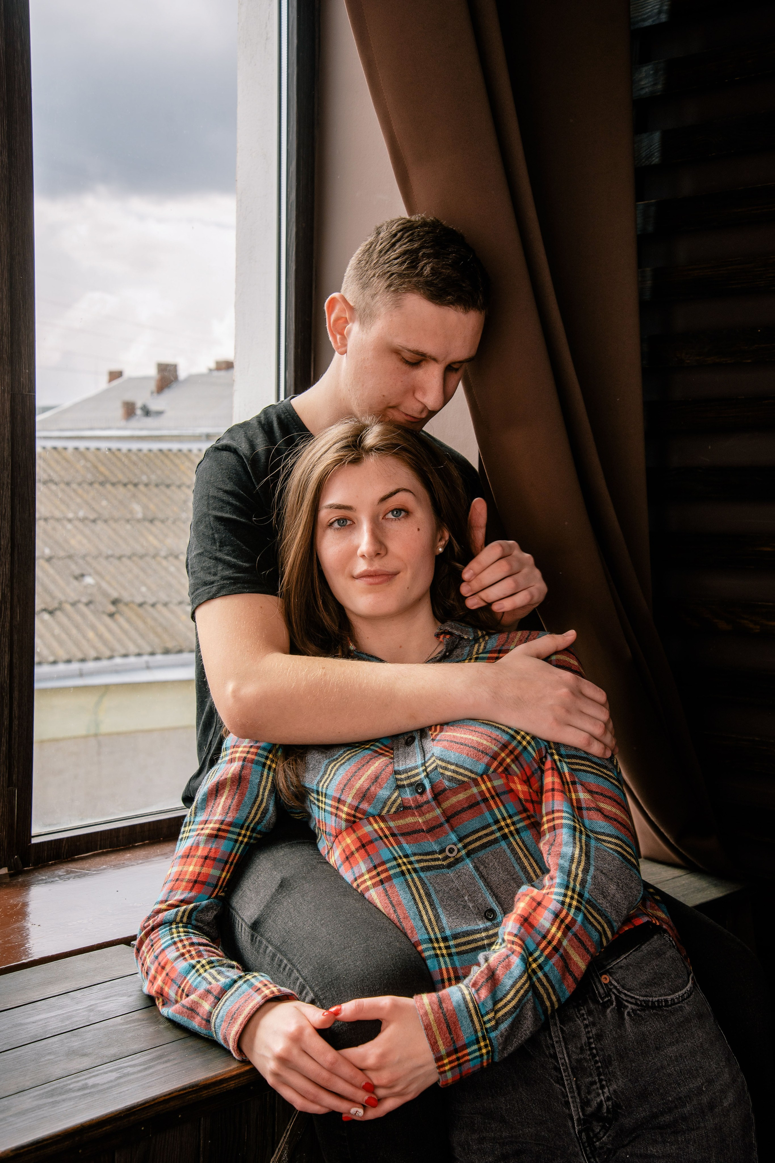 Zwei Personen posieren nah beieinander vor dunklem Hintergrund, modernes emotionales Porträt.