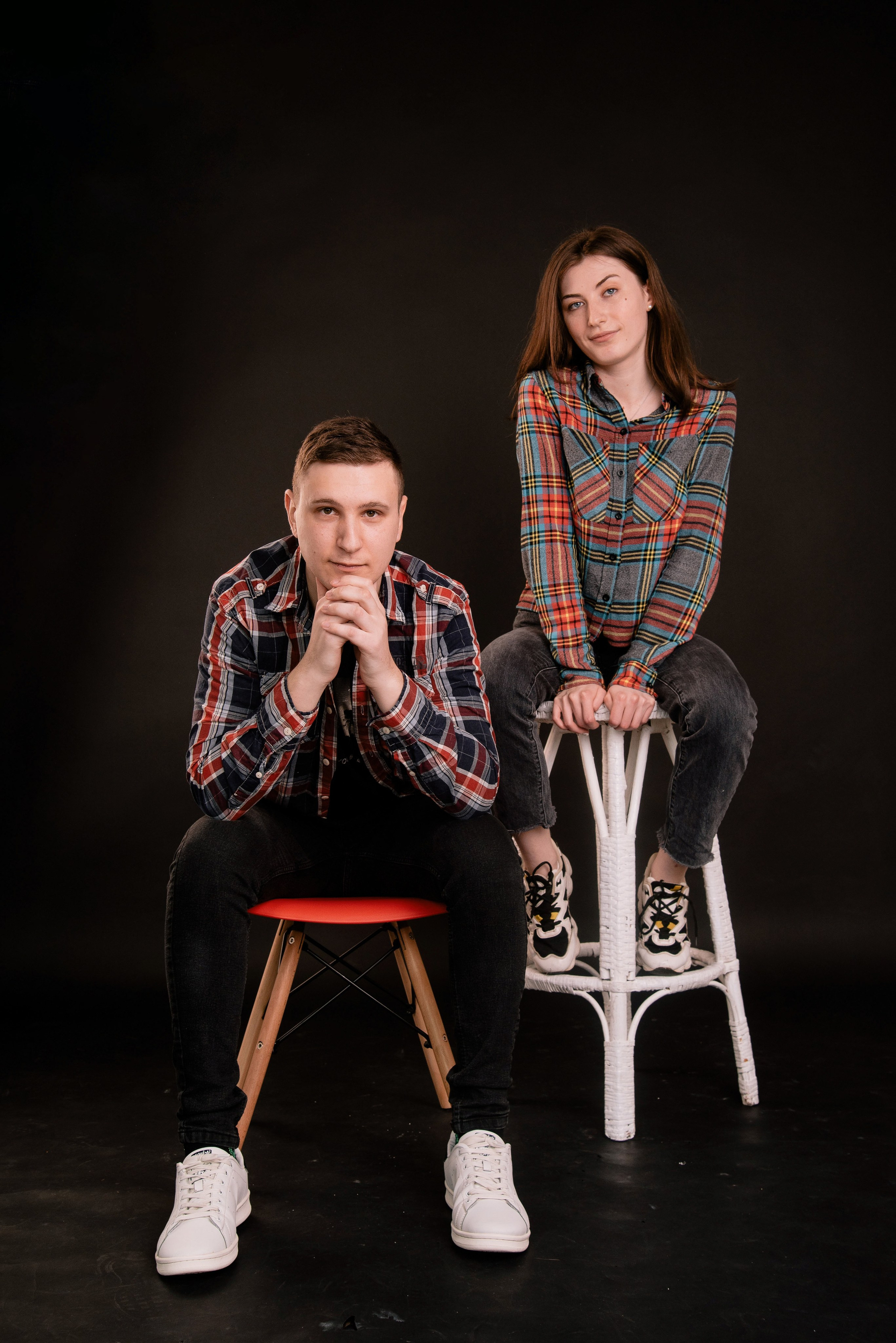 Zwei Personen posieren kreativ im Studio auf schwarzem Hintergrund, modernes und professionelles Porträtfoto.