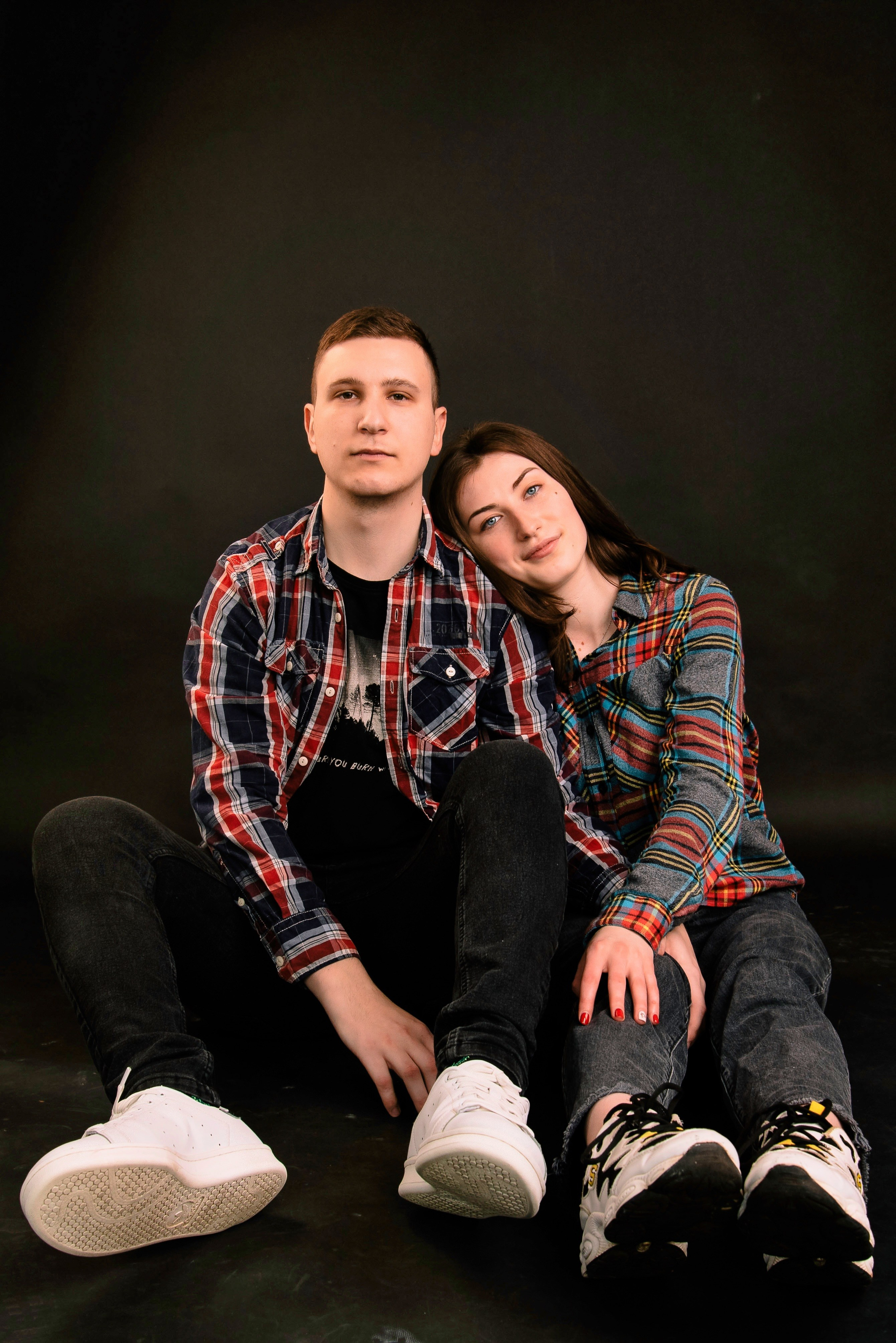 Eine Person sitzt auf dem Boden im Studio und blickt in die Kamera, weiches, modernes Porträt.