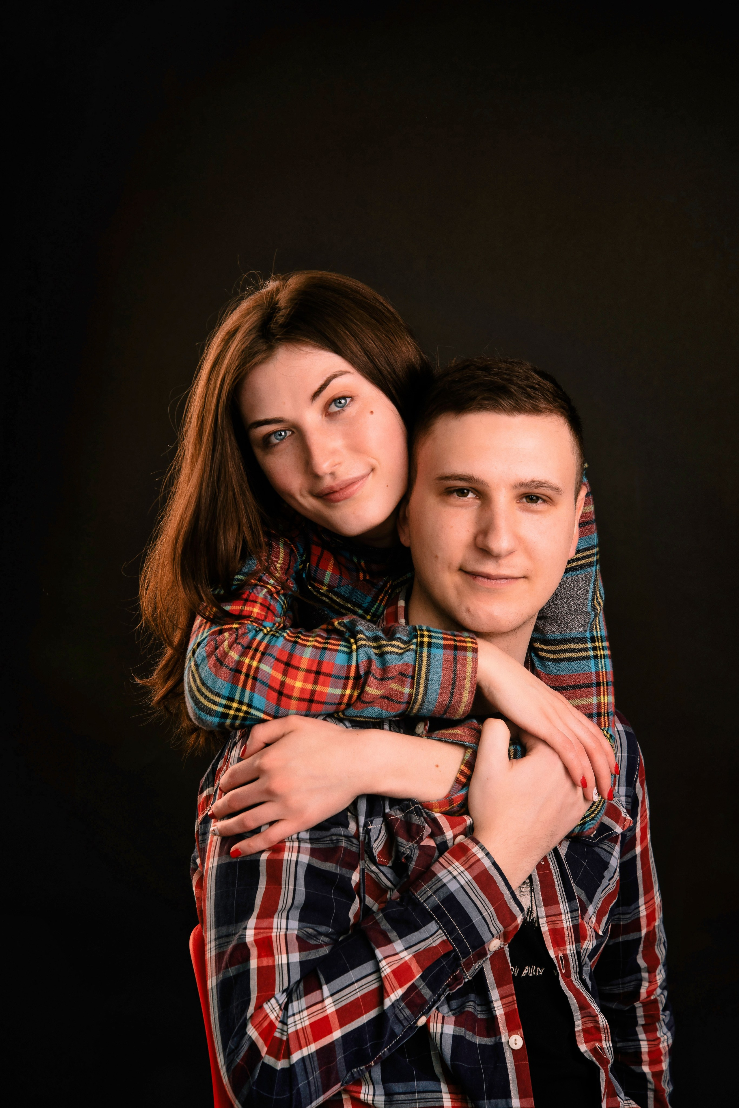 Eine Person steht hinter der anderen und blickt nach vorn, warmes Licht, modernes Paarporträt.