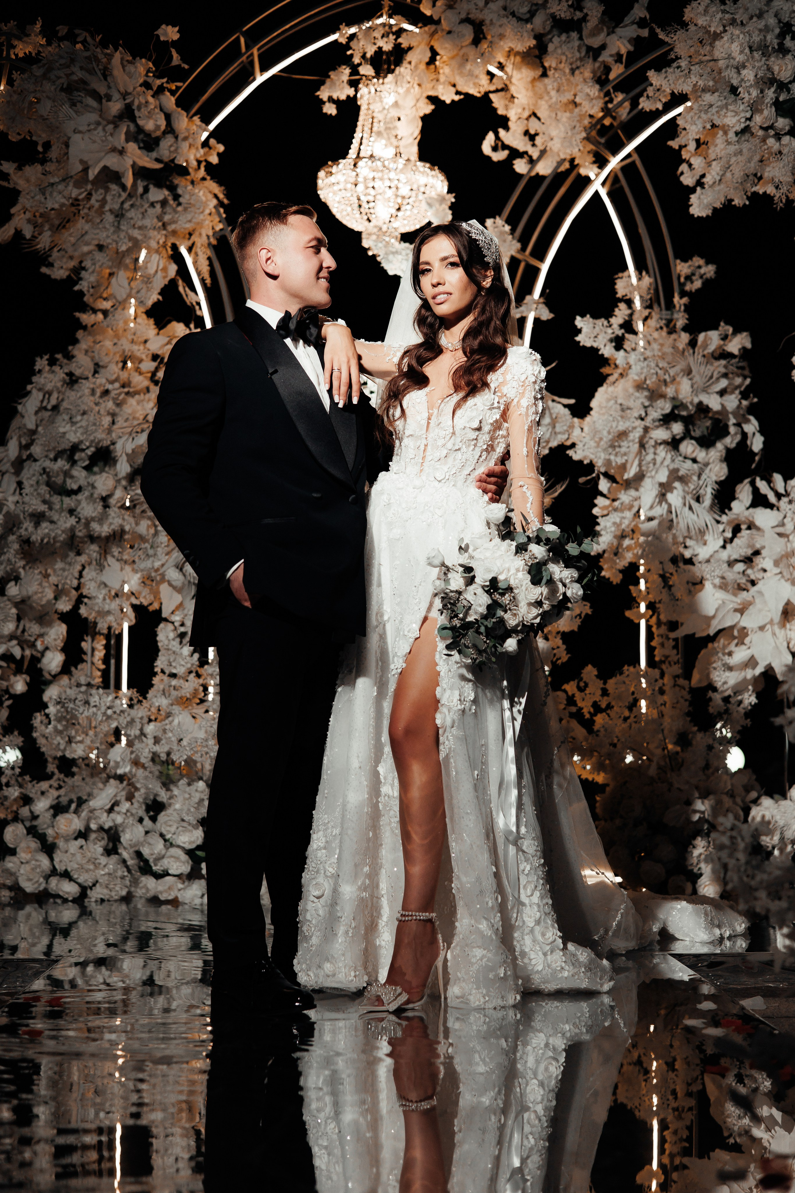 молодожены стоят у свадебной арки во время церемонии