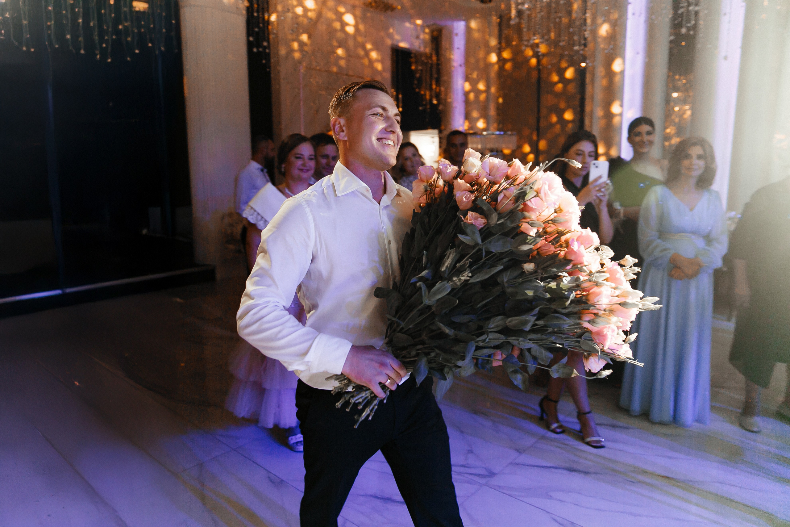 жених несет букет роз невесте на свадьбе 