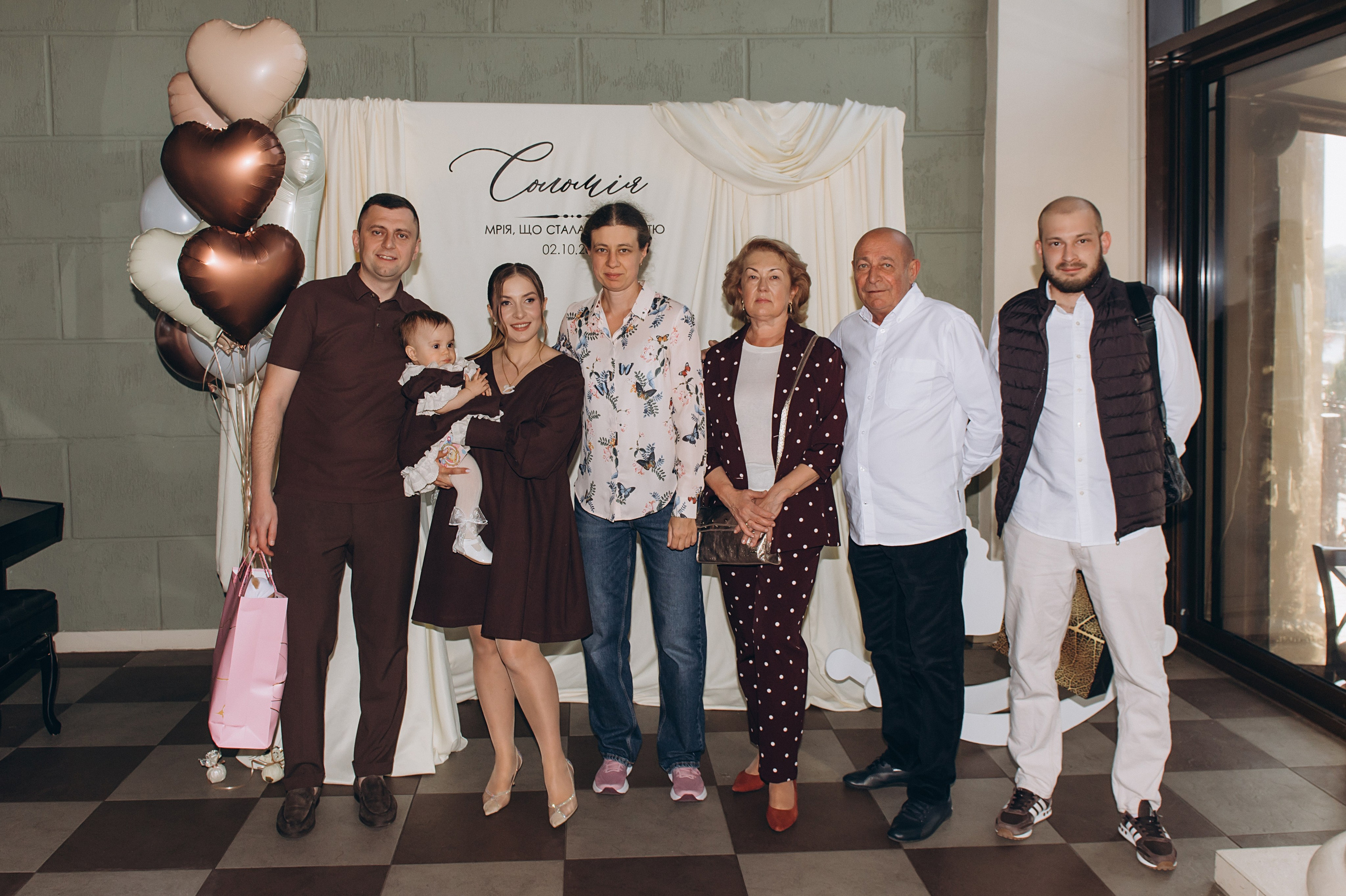 Дитина з хресним і хресною на святкуванні першого дня народження.