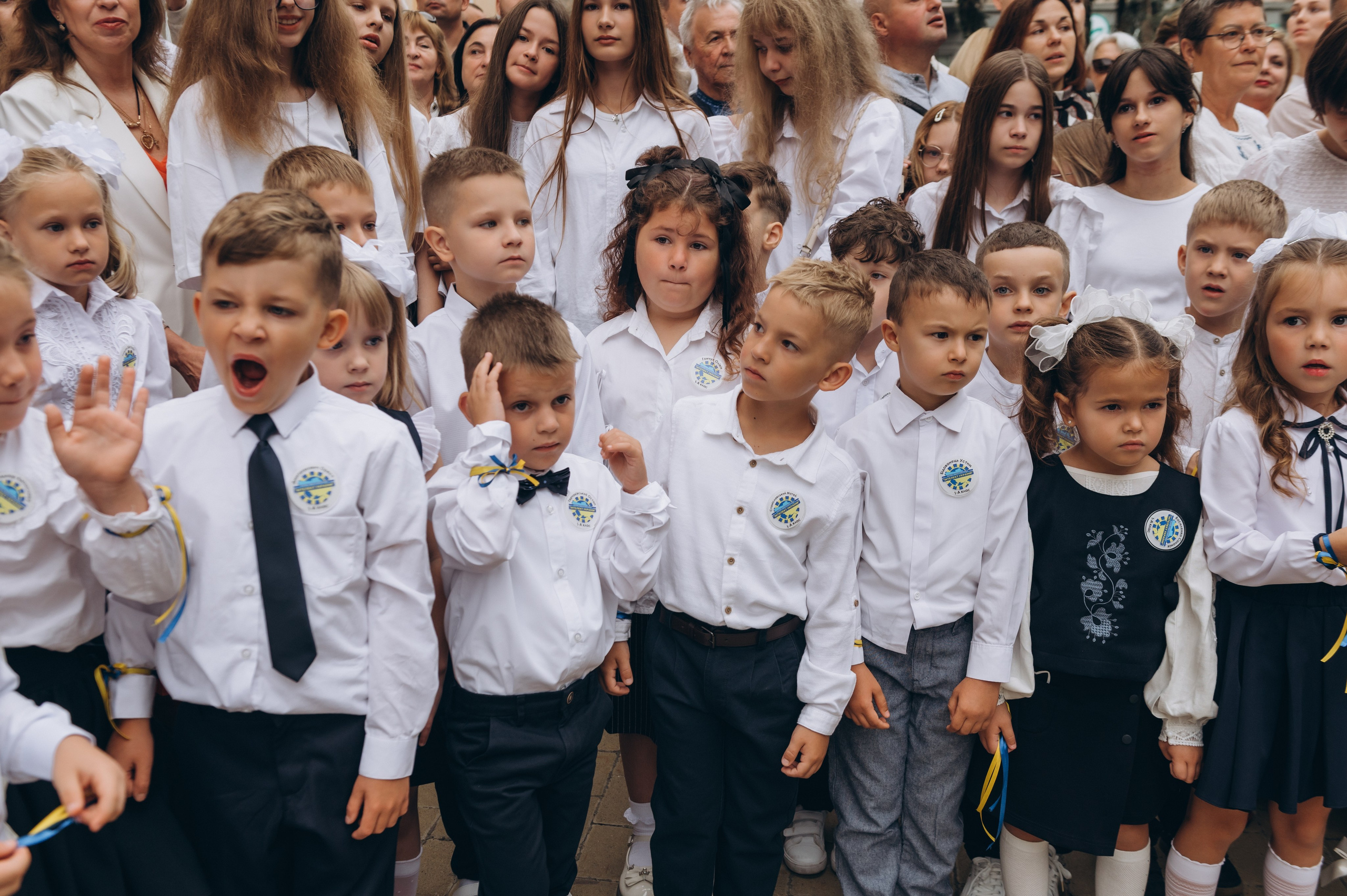 Першокласники стоять на урочистій лінійці 1 вересня з квітами.