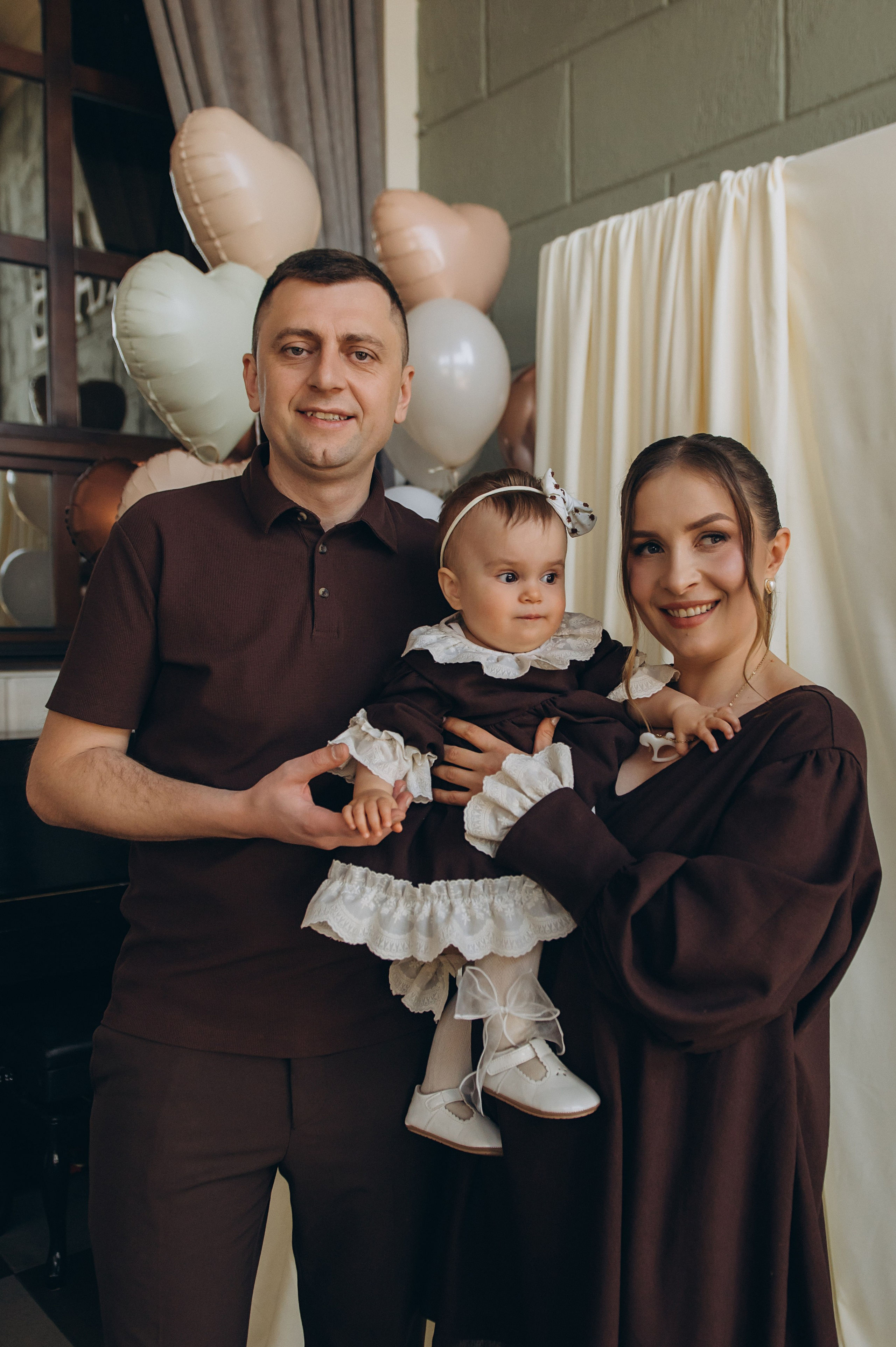 Дитина з хресним і хресною на святкуванні першого дня народження.