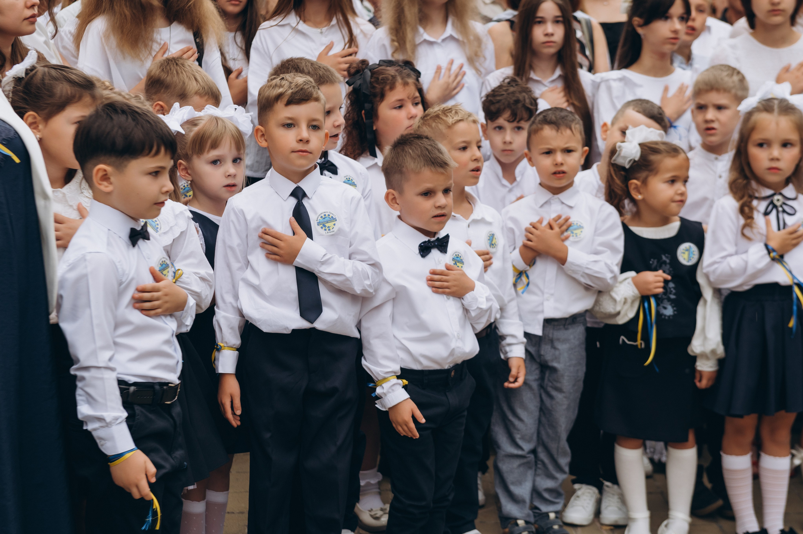 Першокласники стоять на урочистій лінійці 1 вересня з квітами.