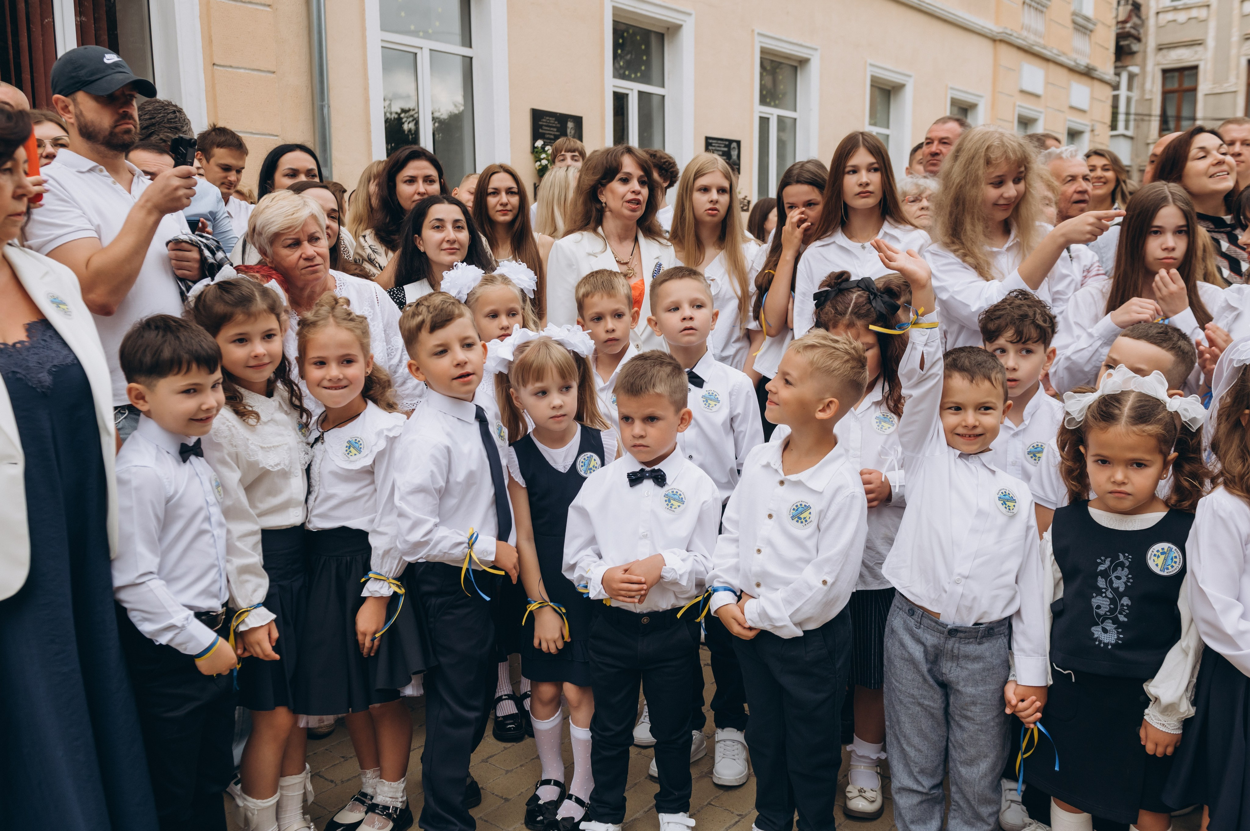 Першокласники стоять на урочистій лінійці 1 вересня з квітами.