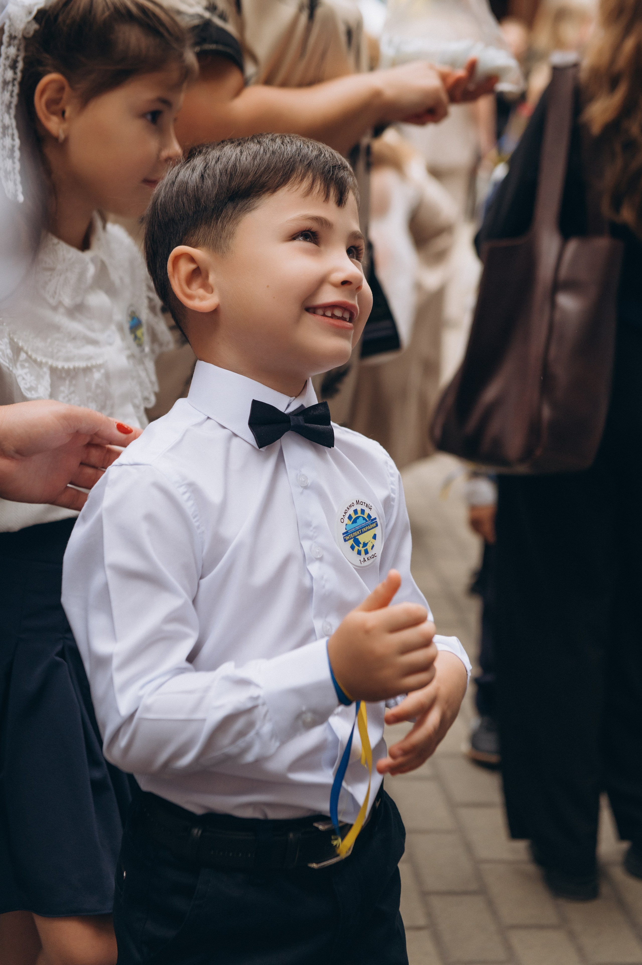 Першокласнику одягають синьо-жовту стрічку під час свята 1 вересня.