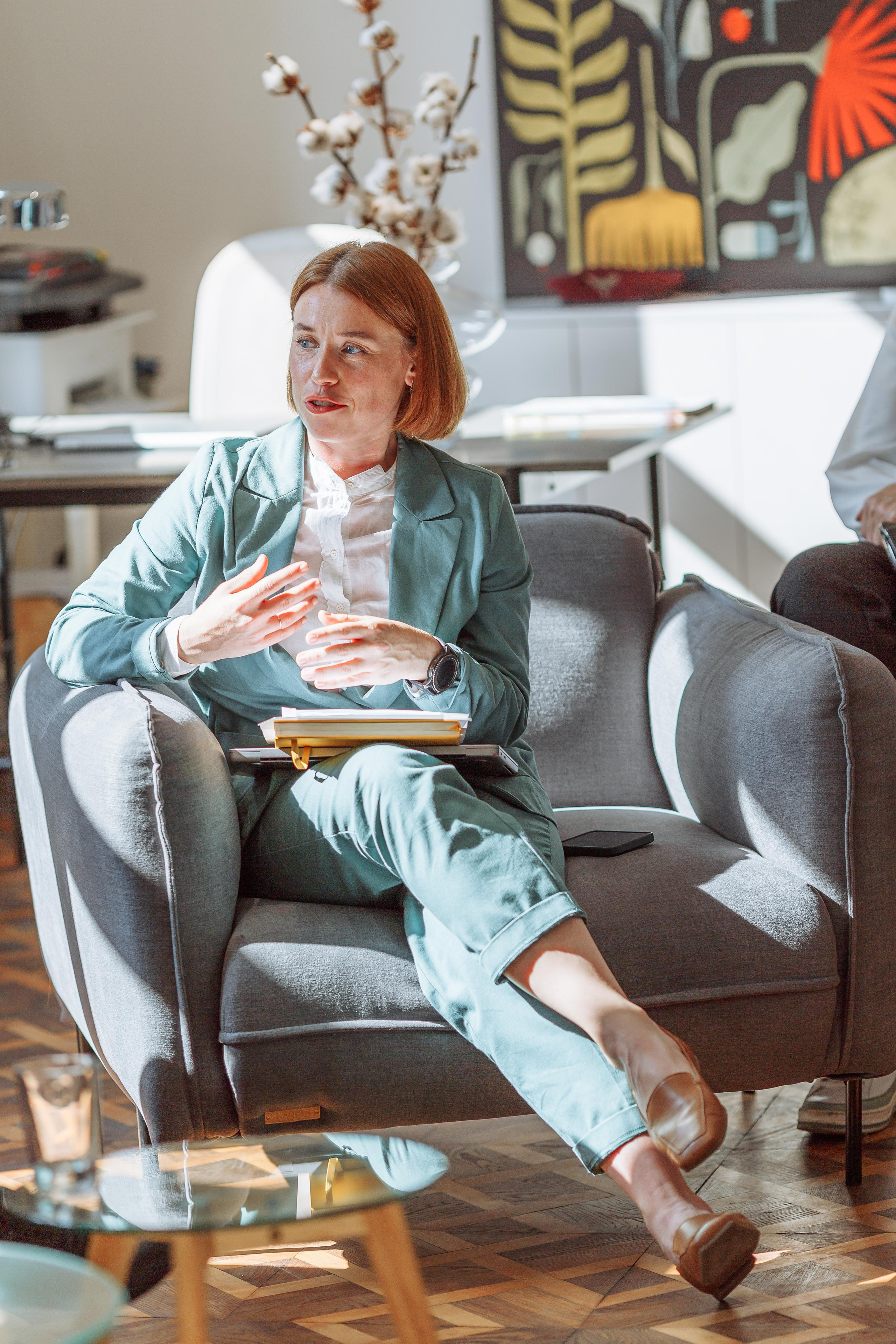 Бізнес-вумен в красивому м'ятному костюмі сидить в кріслі в офісі