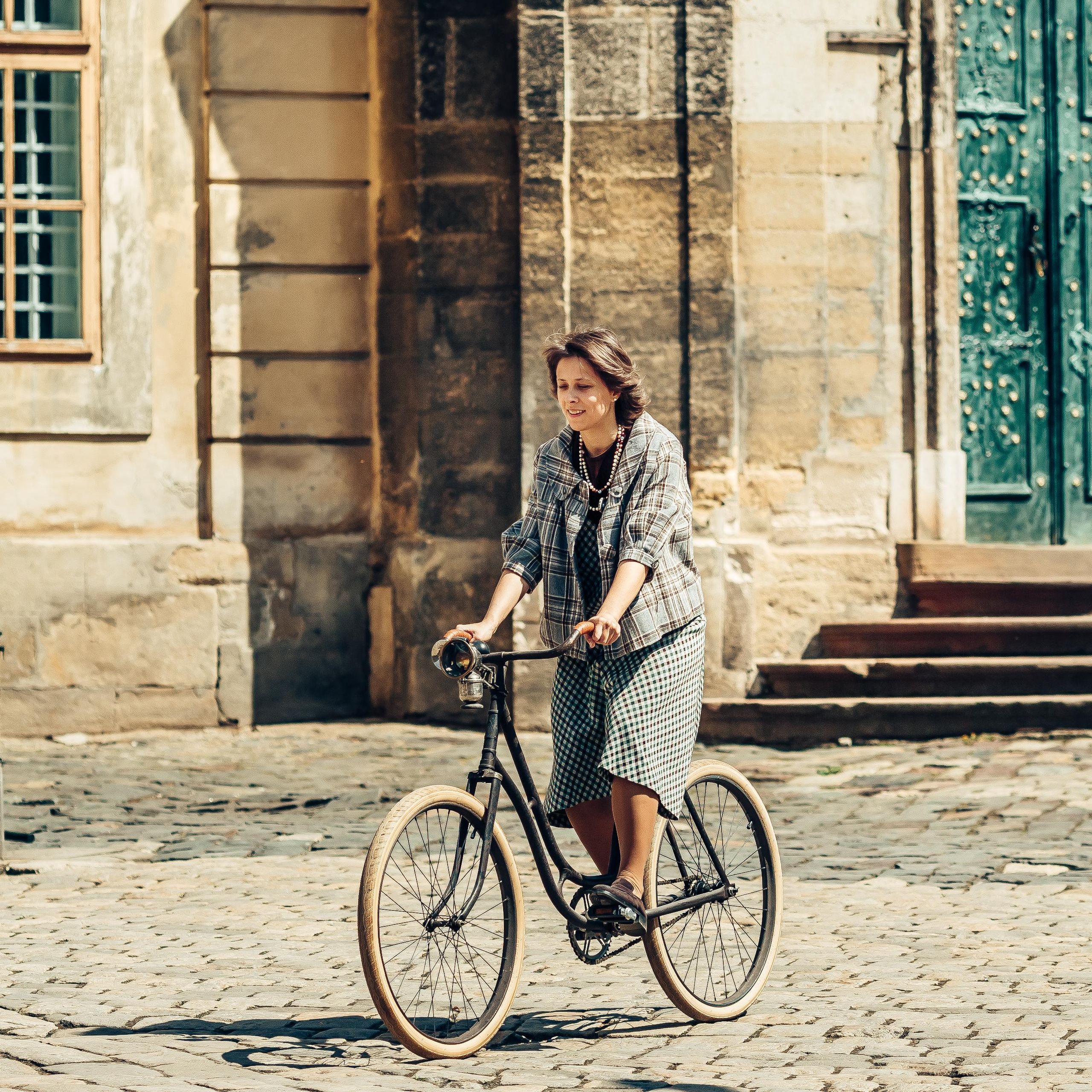 Кобіта на велосипеді їде по бруківці у Львові