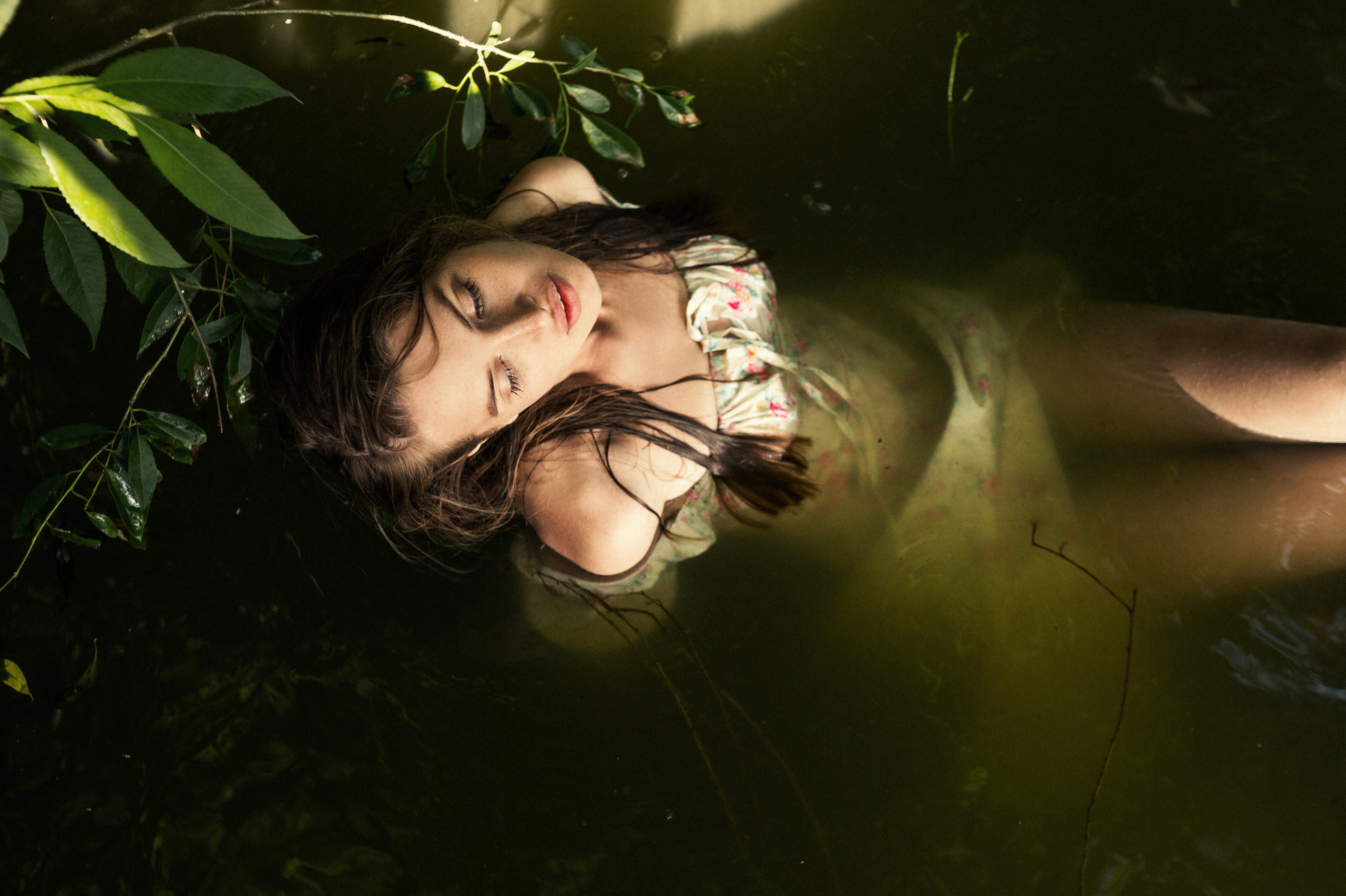 Вид сверху. Девушка в воде на озере в платье, часть тела находится под водой 